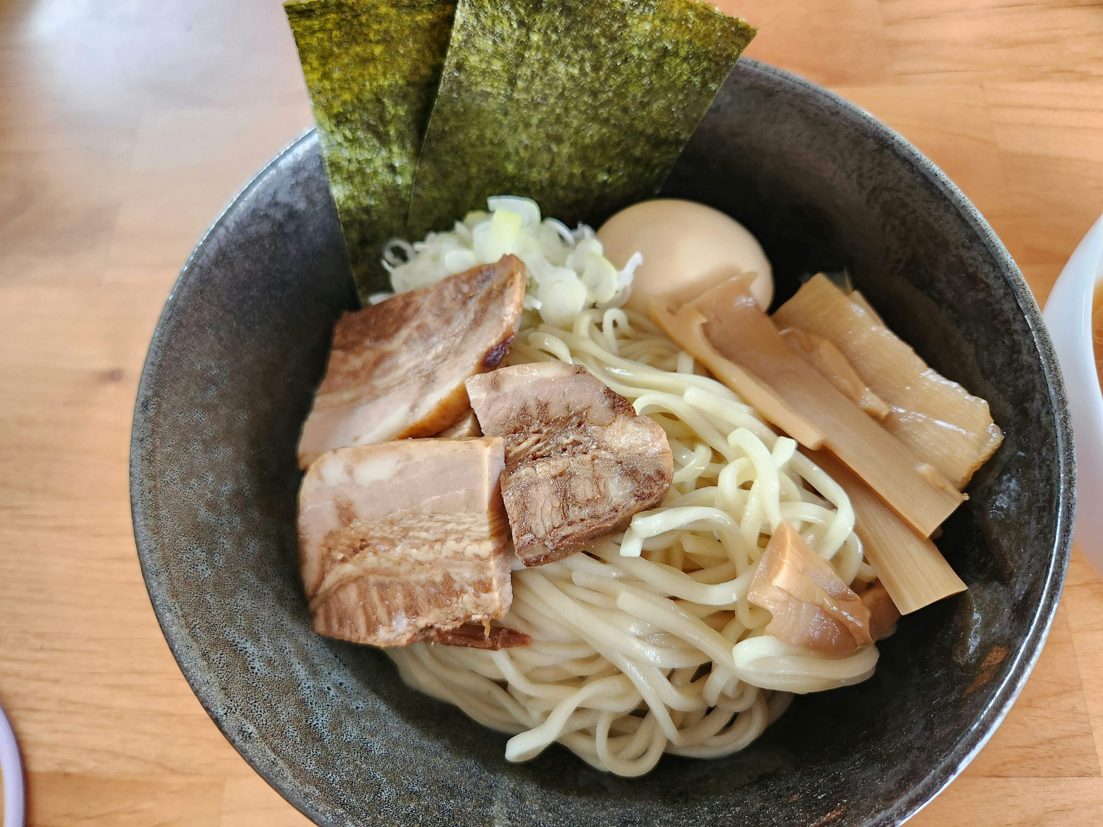 Bát ramen với mì dày được phủ với lát thịt chashu, trứng luộc, menma và nori