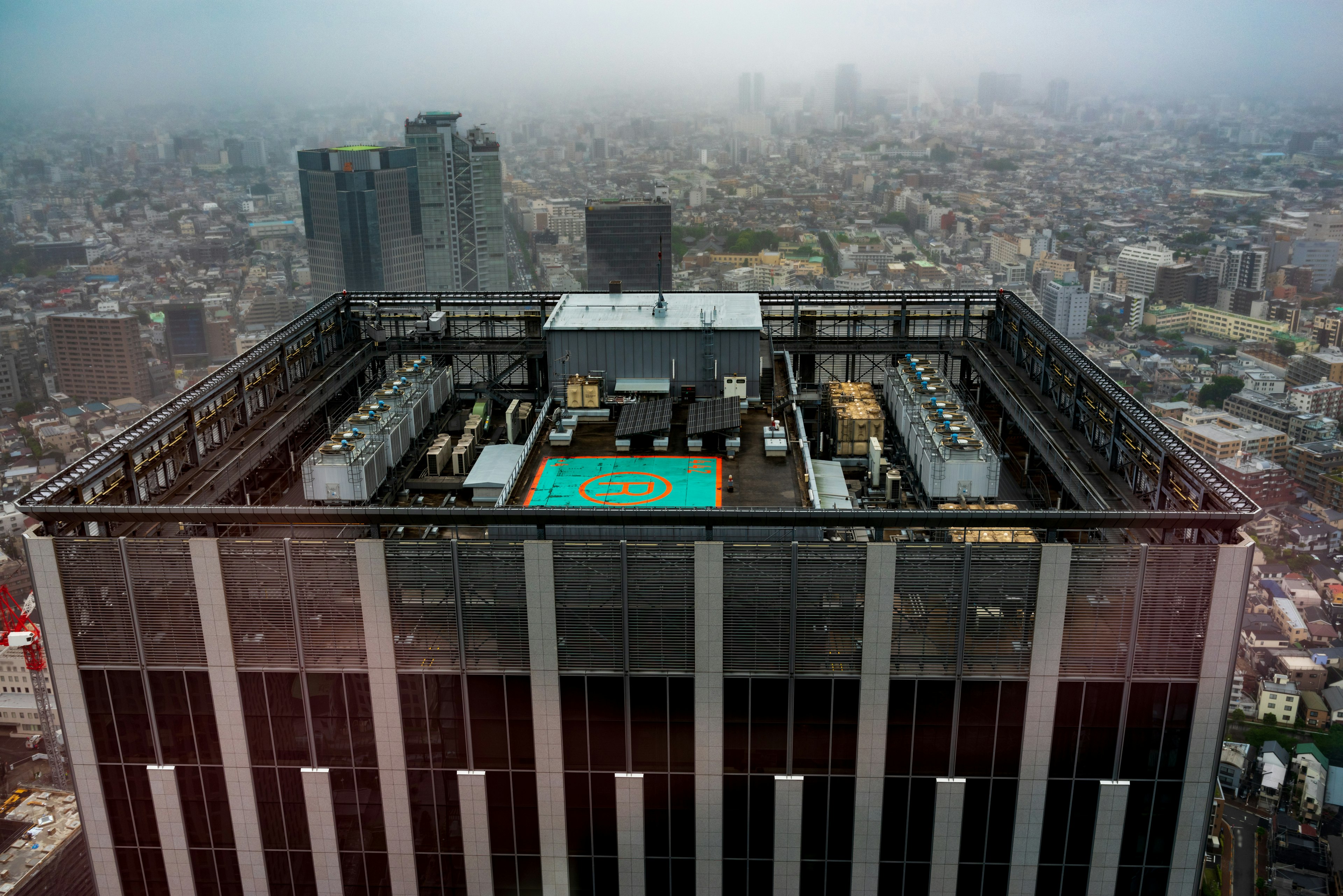 View from the rooftop of a skyscraper overlooking a foggy cityscape