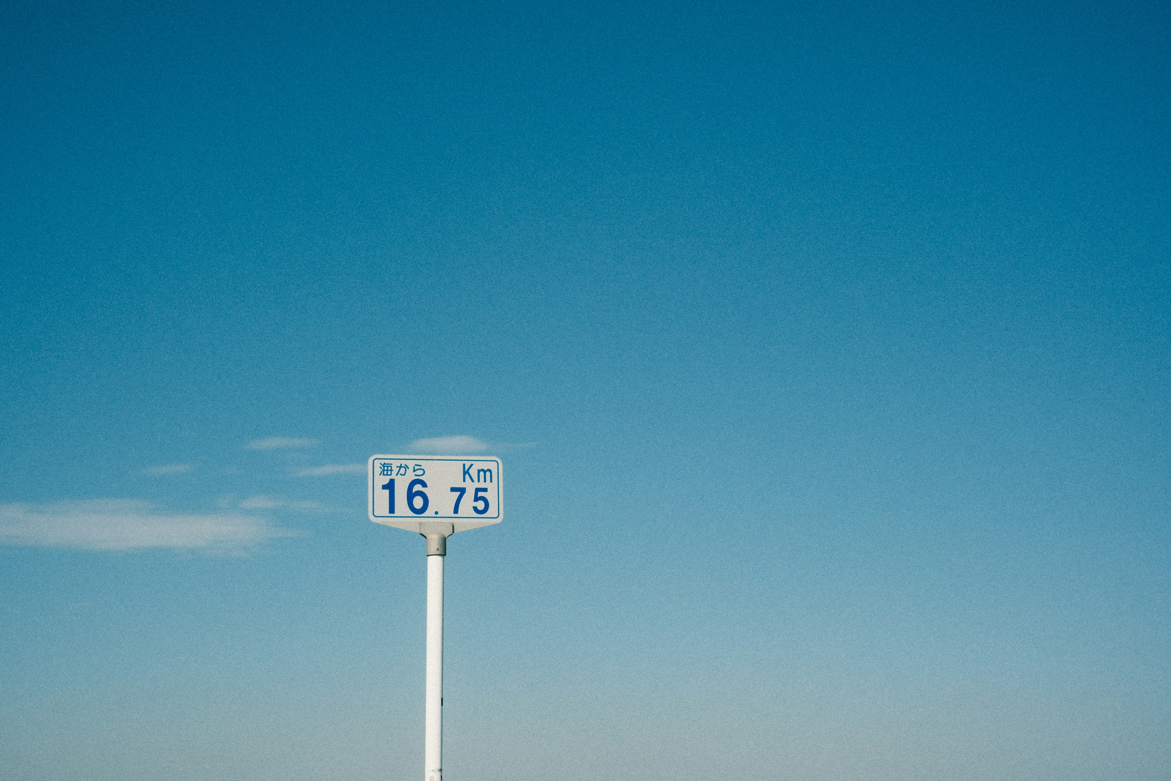 Ein weißes Schild mit Zahlen unter einem klaren blauen Himmel