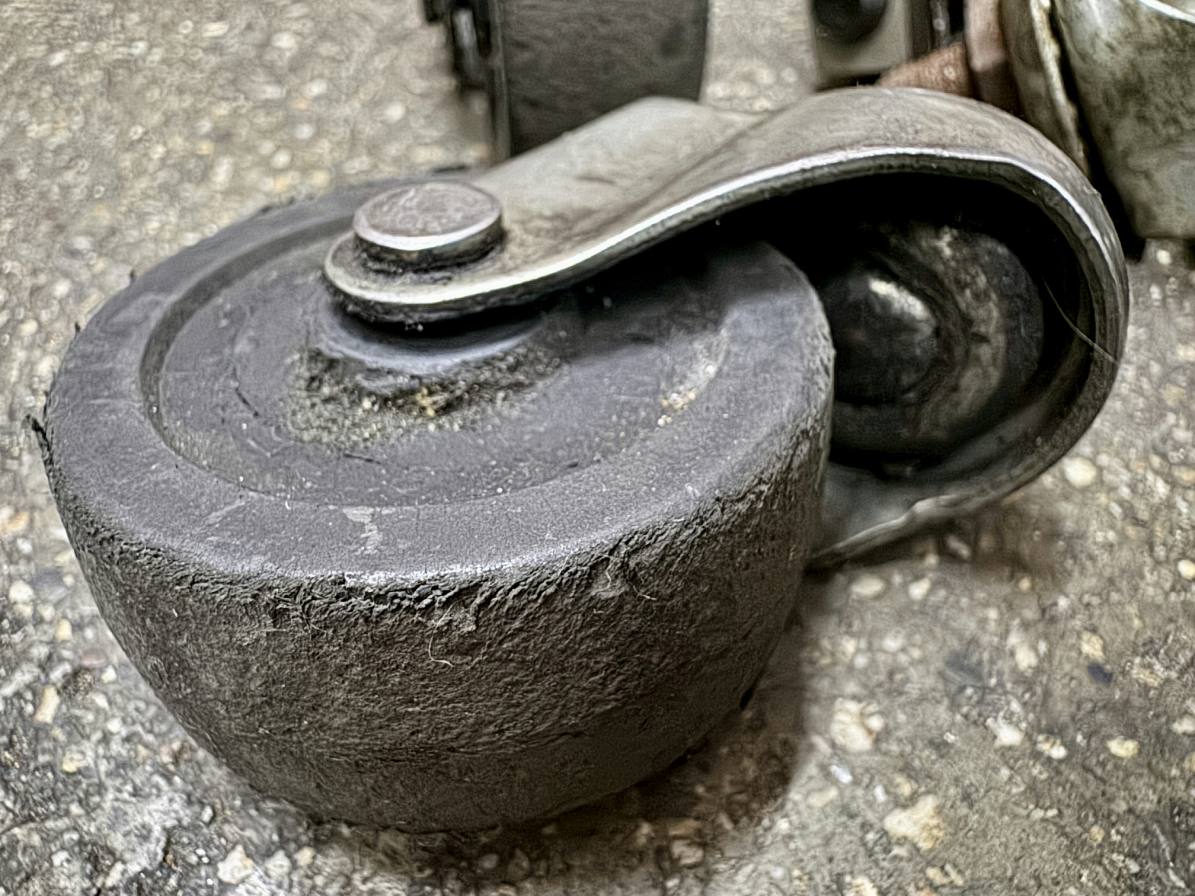 Close-up of an old caster wheel made of metal and rubber with a worn surface