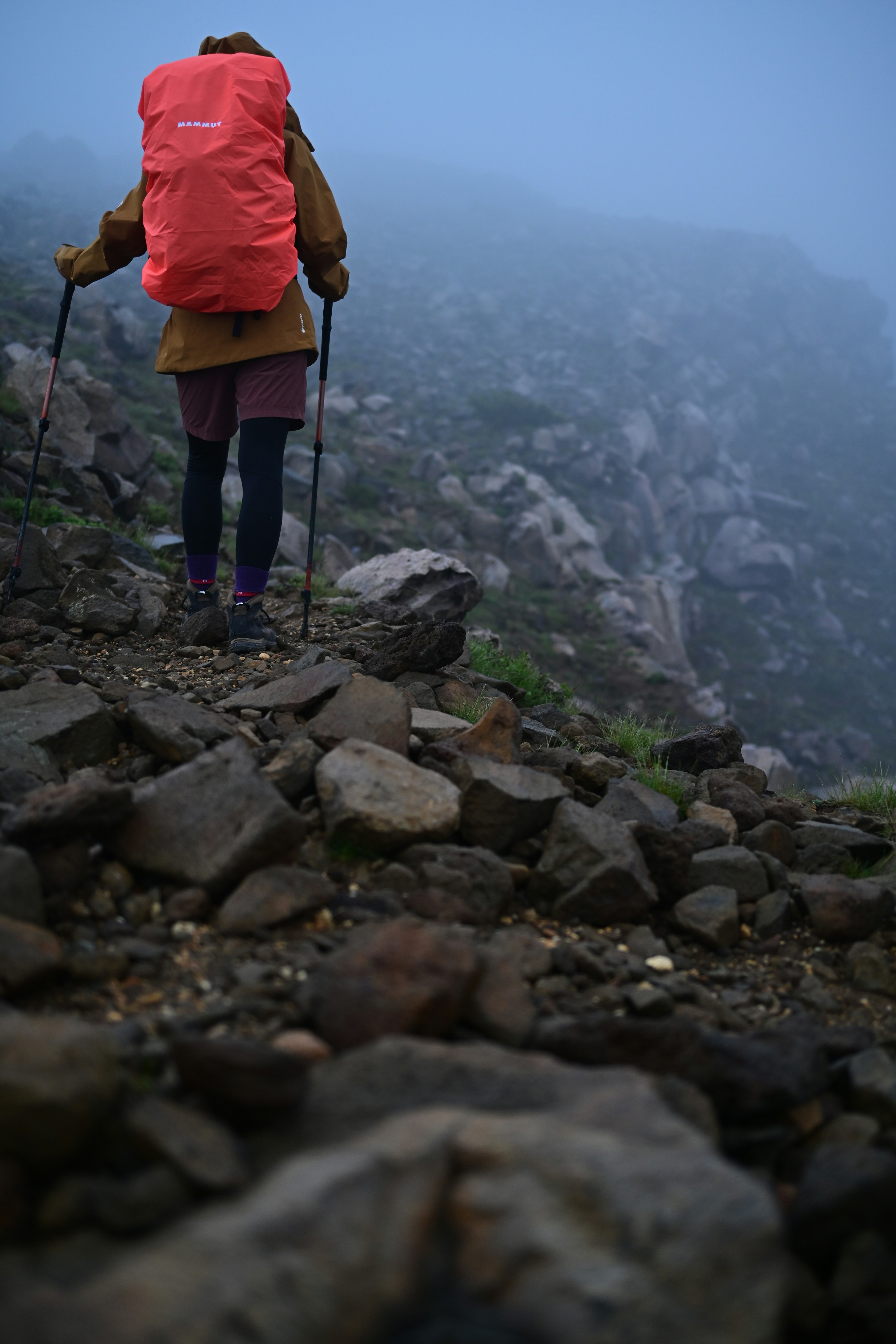 Hiker walking through fog wearing a red backpack