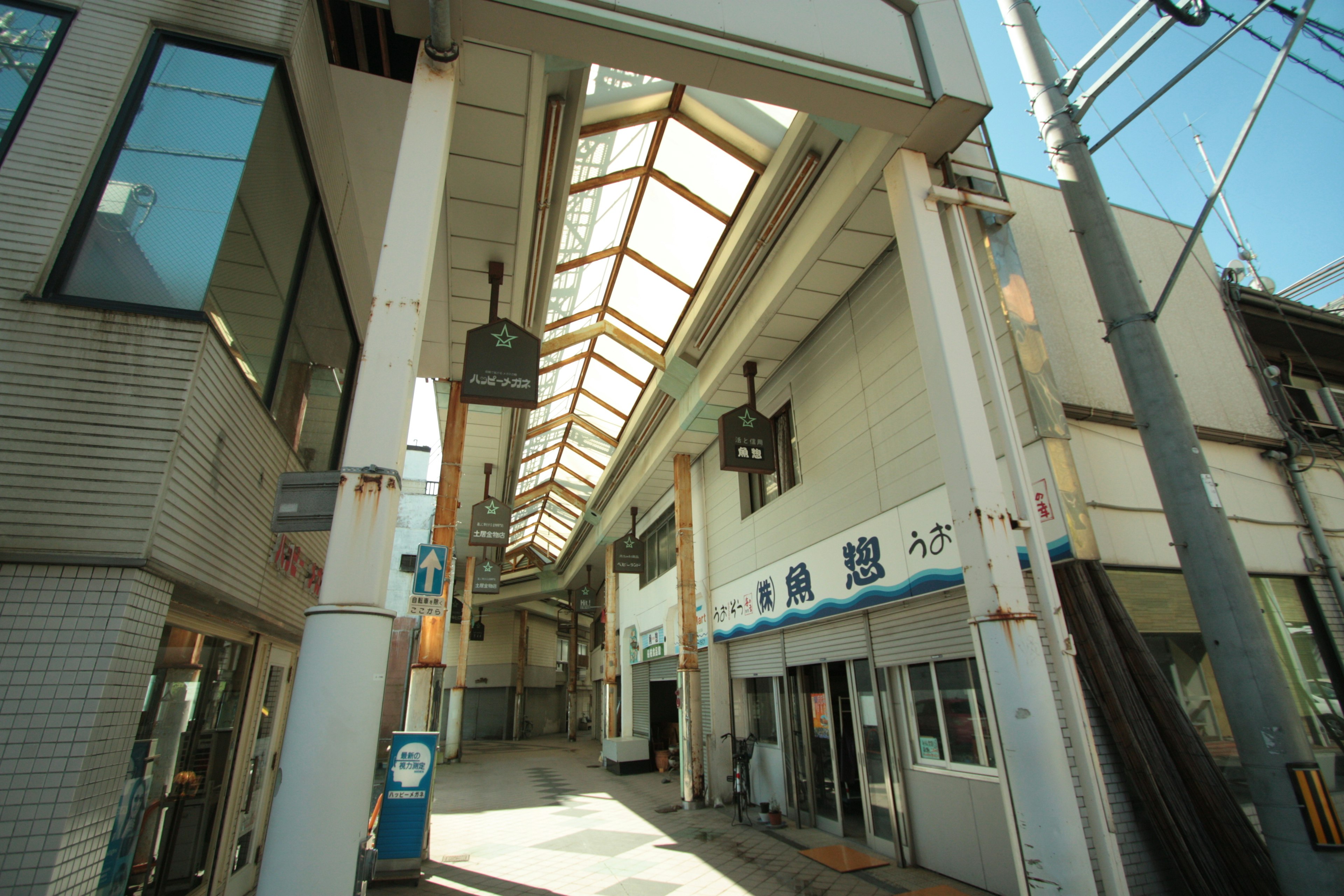 View of a covered street with sunlight streaming through the arcade buildings visible