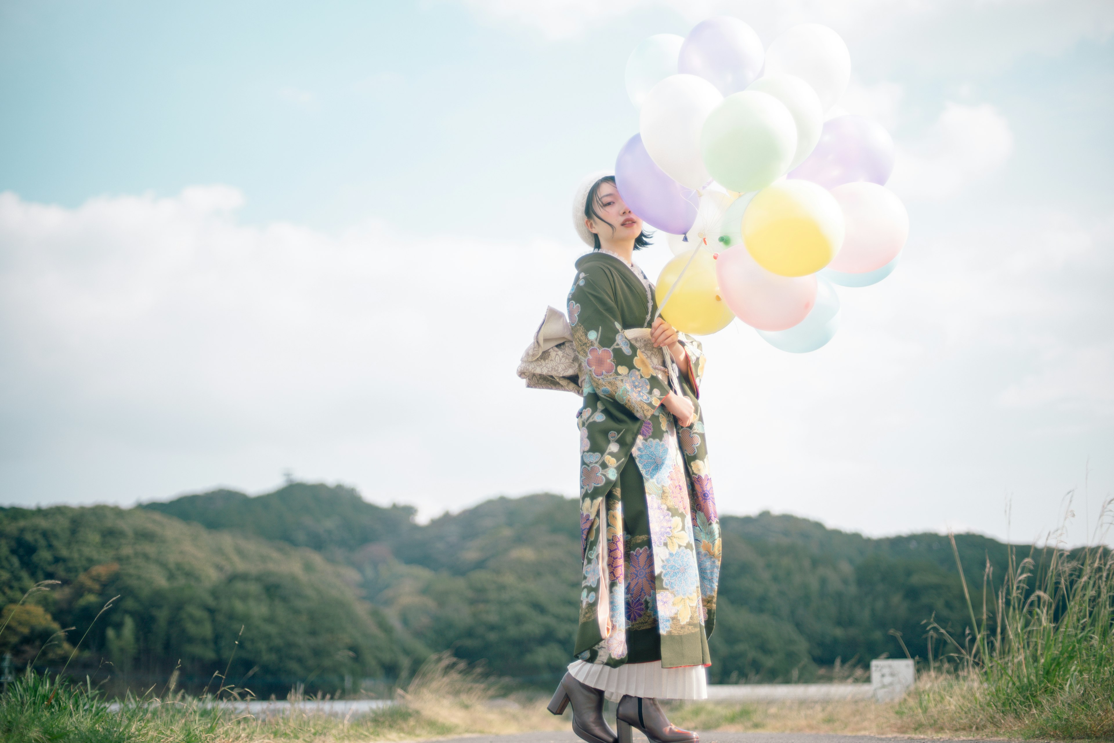 Una donna sorridente che tiene palloncini colorati in un ambiente esterno panoramico