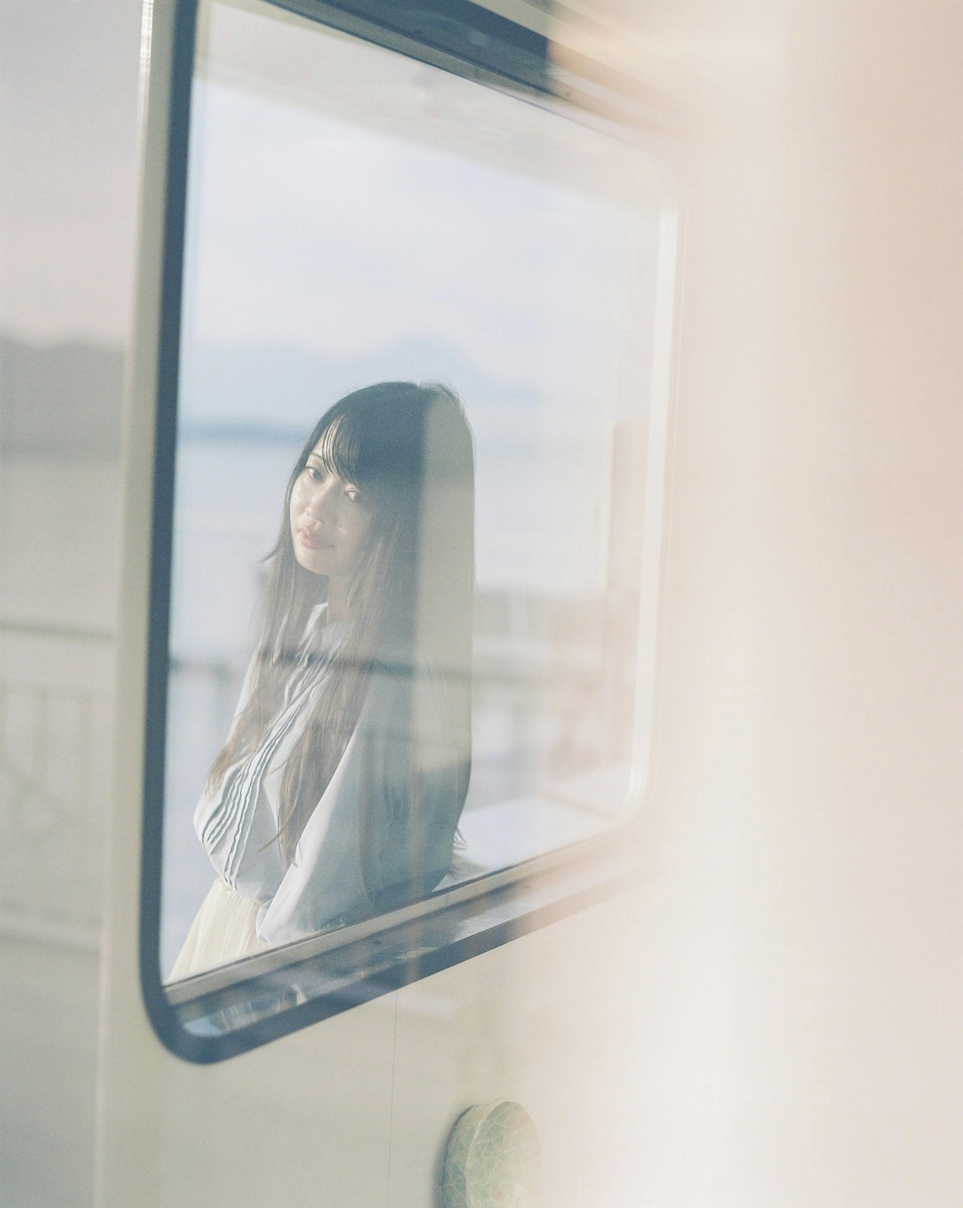 A woman gazing out of a window with a blurred seaside background