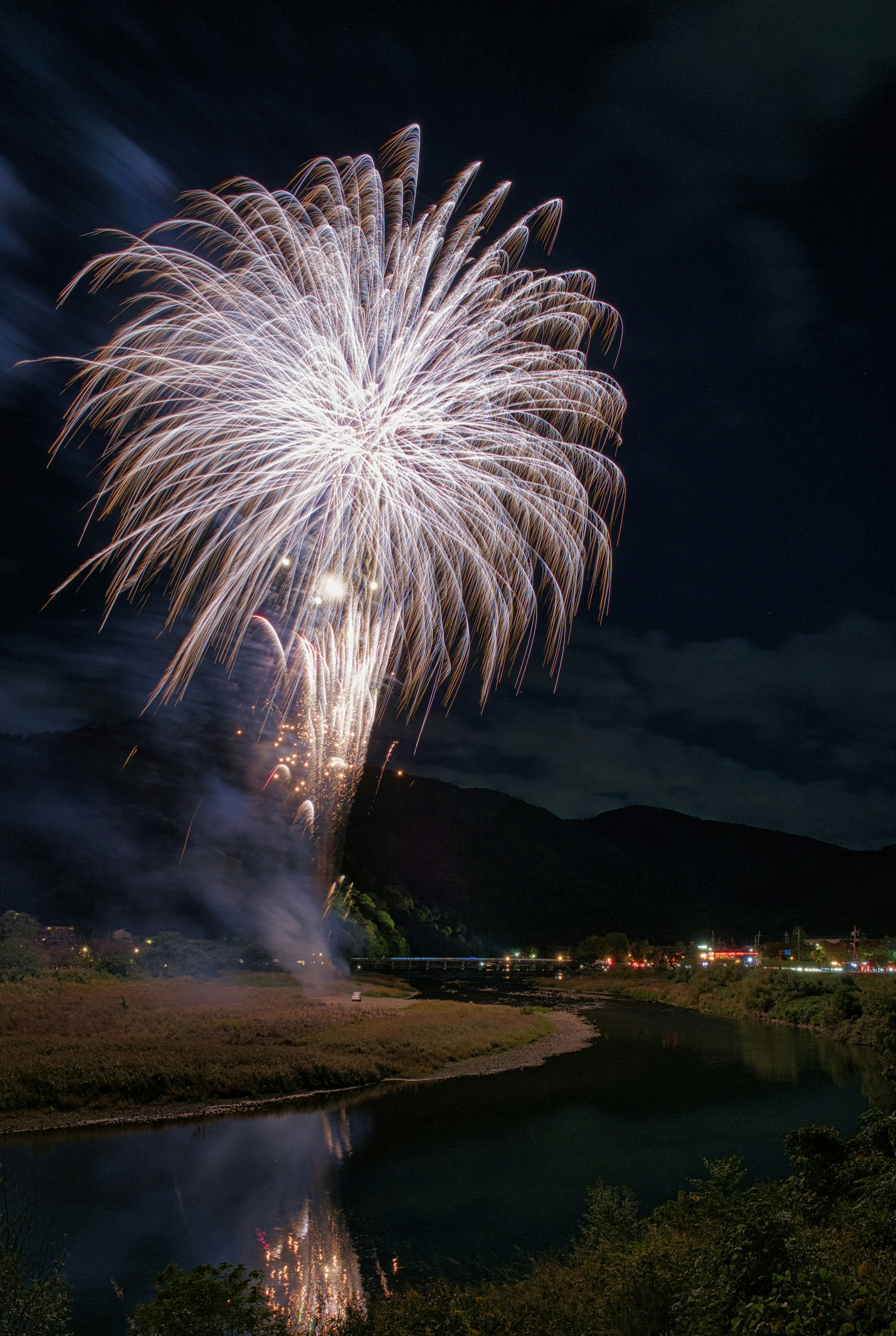 Un grand feu d'artifice s'épanouissant dans le ciel nocturne avec des reflets