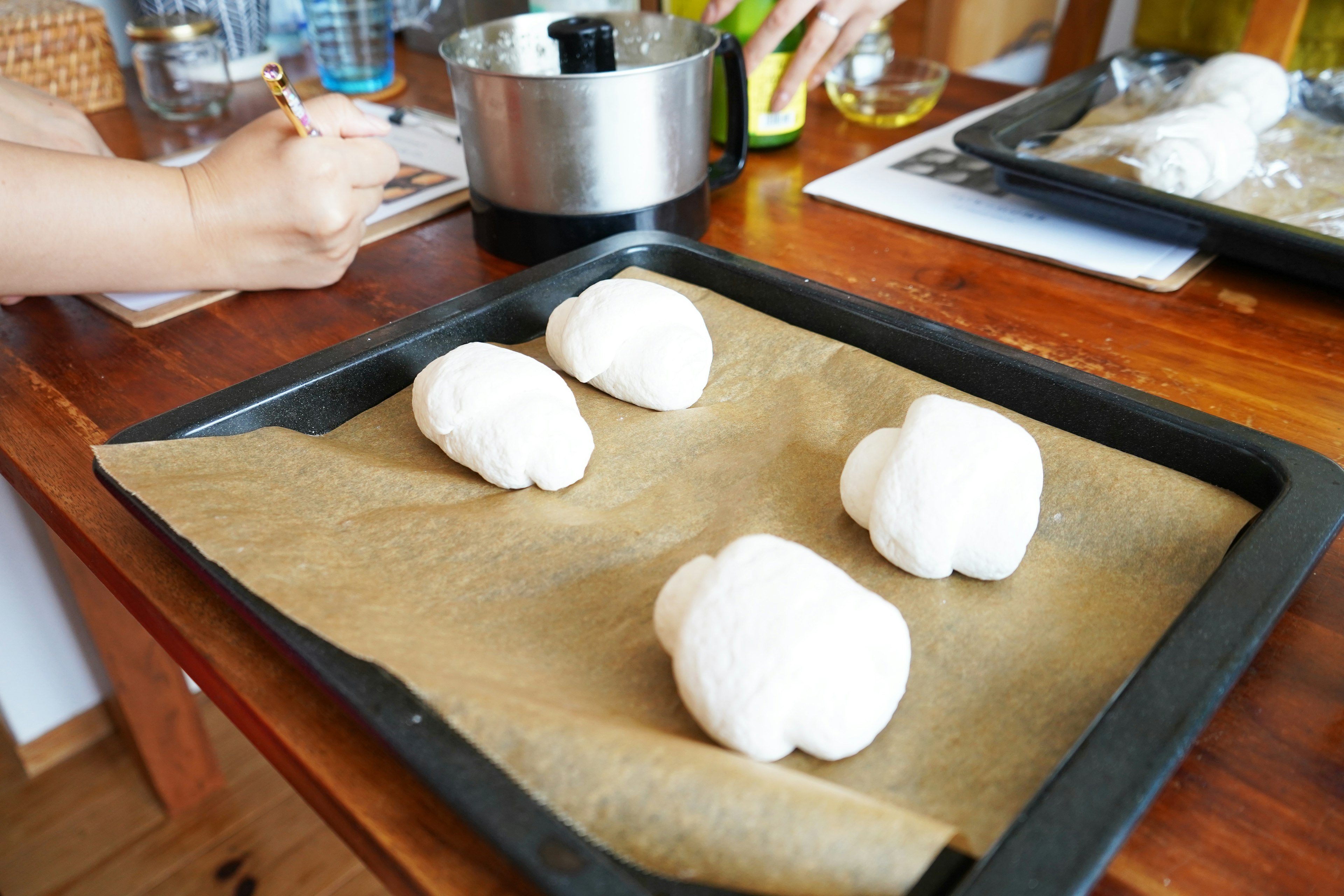 Masa en crecimiento en la cocina cuatro piezas de masa blanca en una bandeja de horno