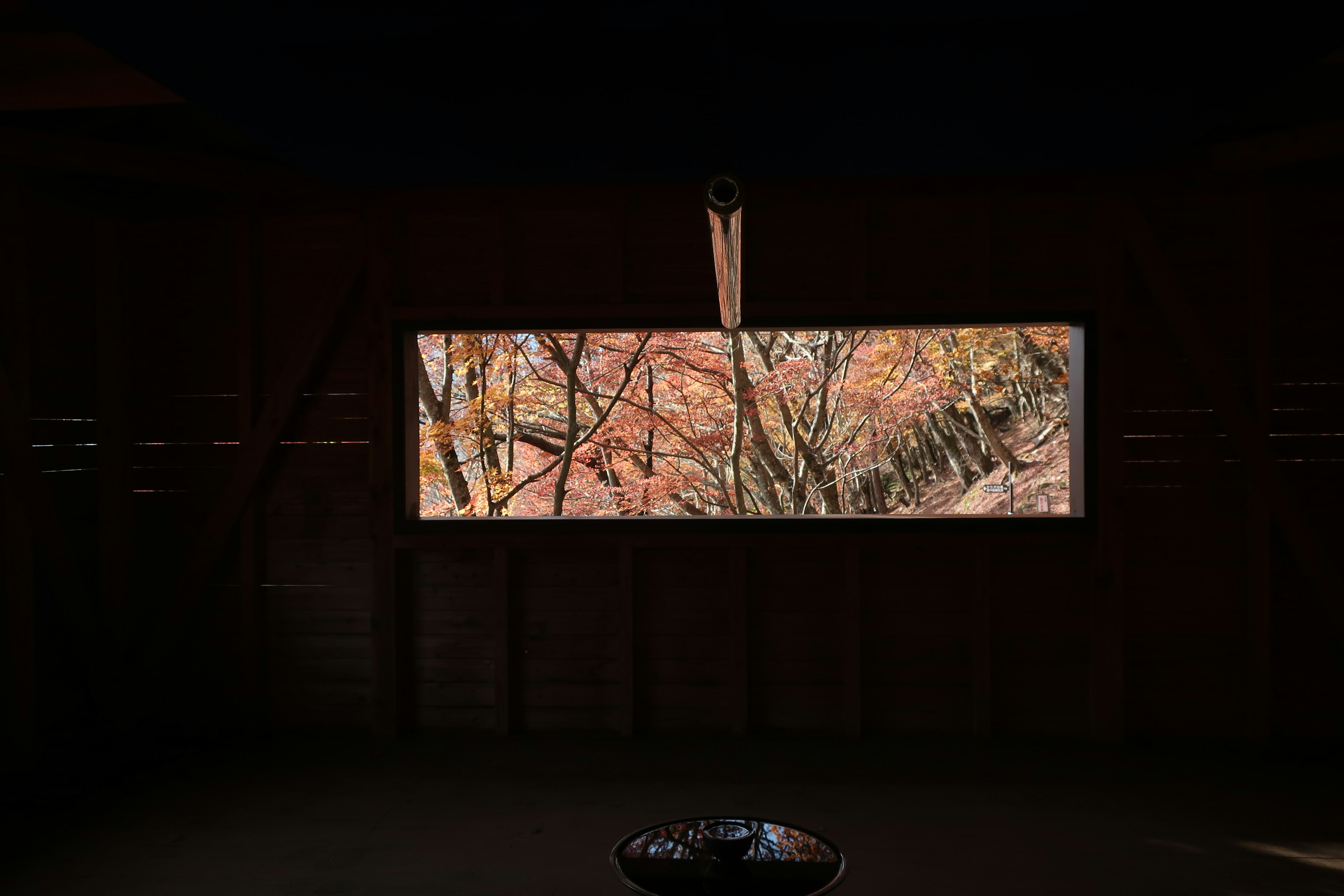 Vue sur le feuillage d'automne à travers une fenêtre en bois avec un intérieur sombre