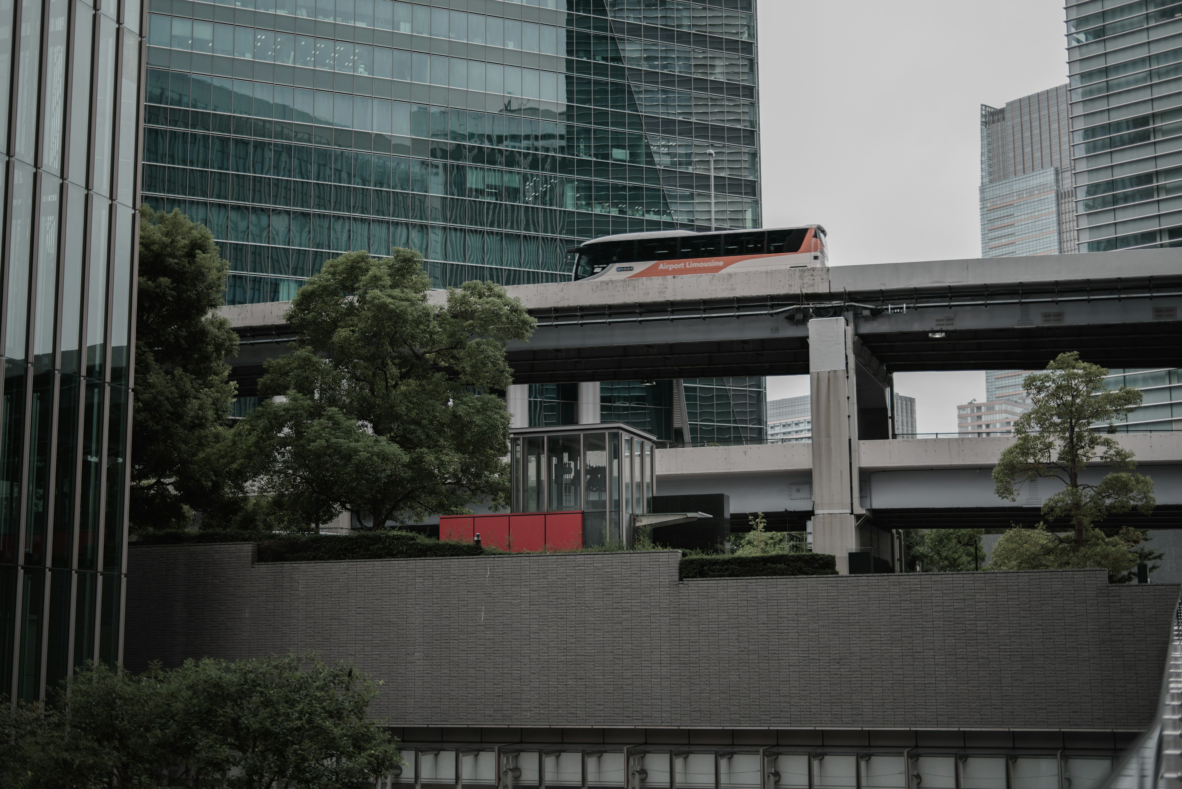 Paisaje urbano con edificios y autopistas elevadas con vegetación y un monorriel