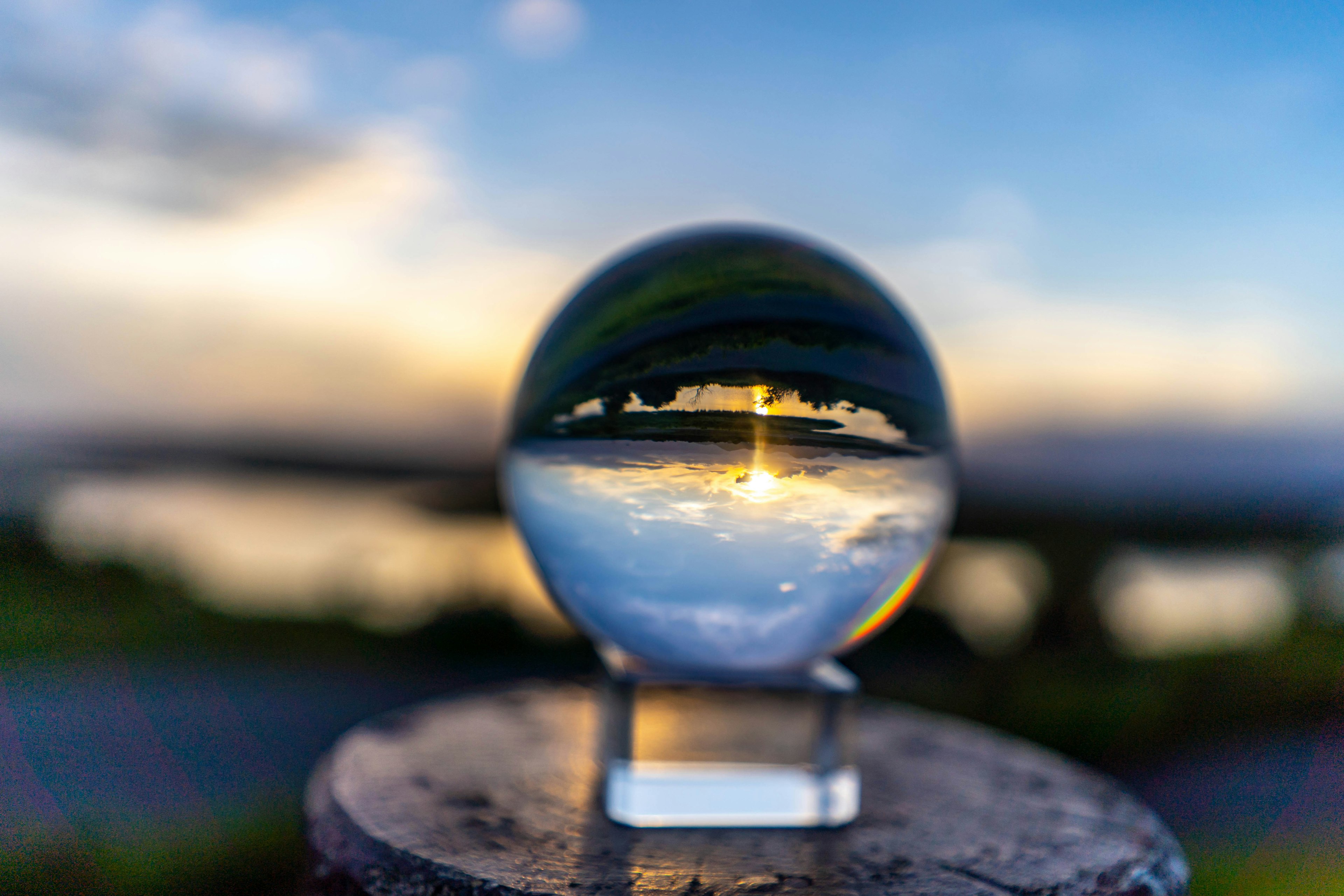 水面に映る夕日と空を捉えたクリスタルボールの写真