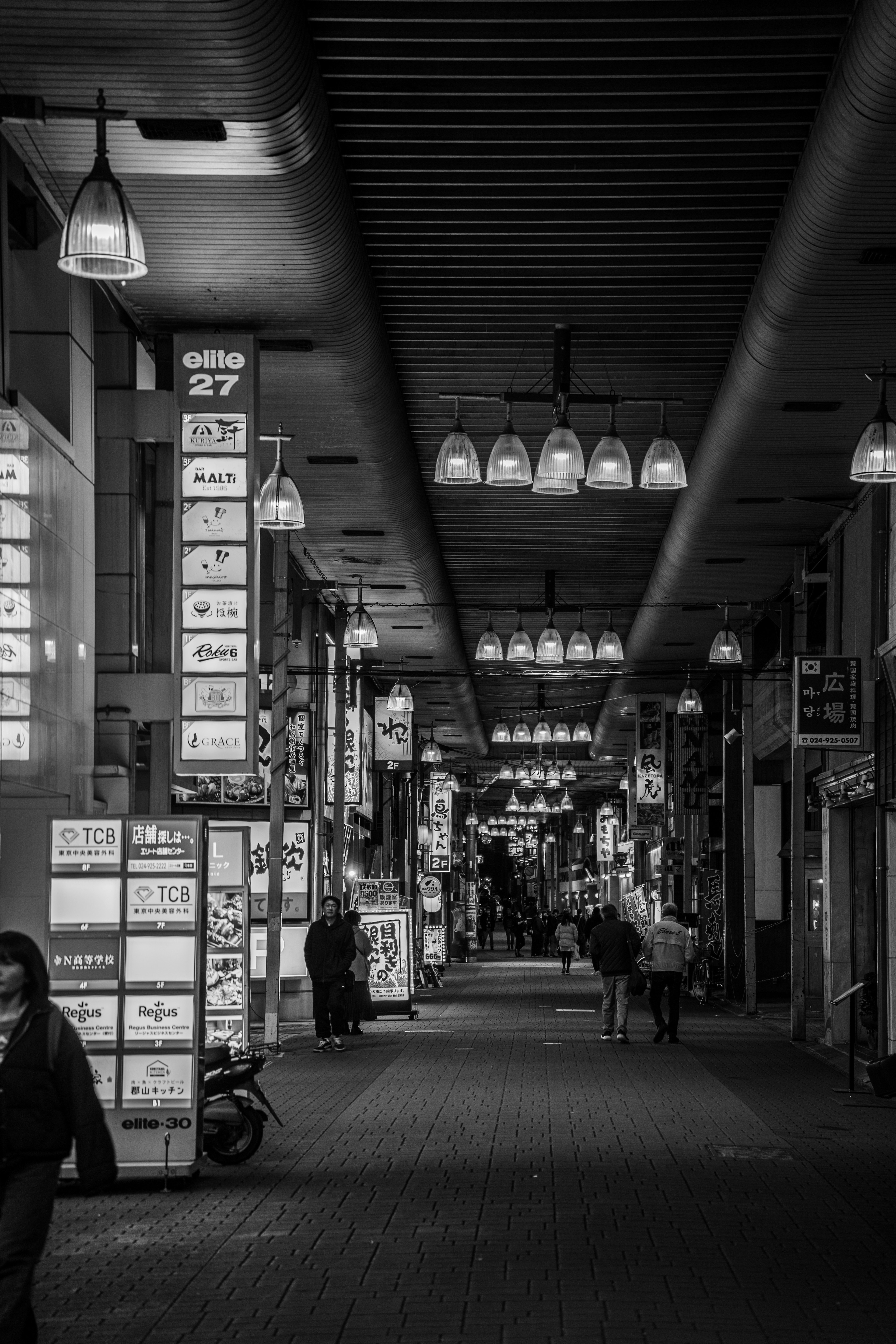 モノクロの商店街の通り 照明が吊るされた天井 看板が並ぶ壁