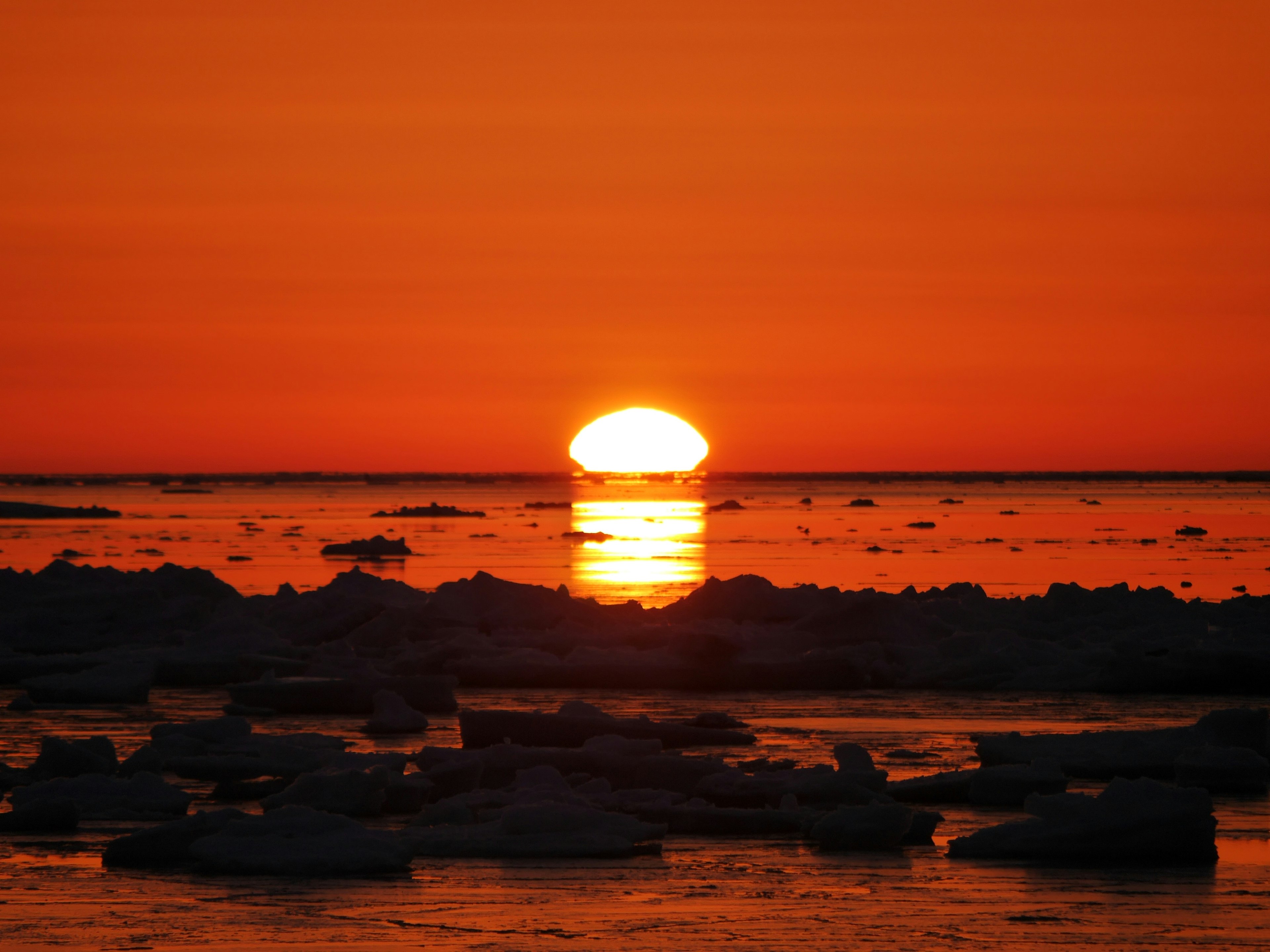 Atardecer sobre aguas heladas con cielo naranja