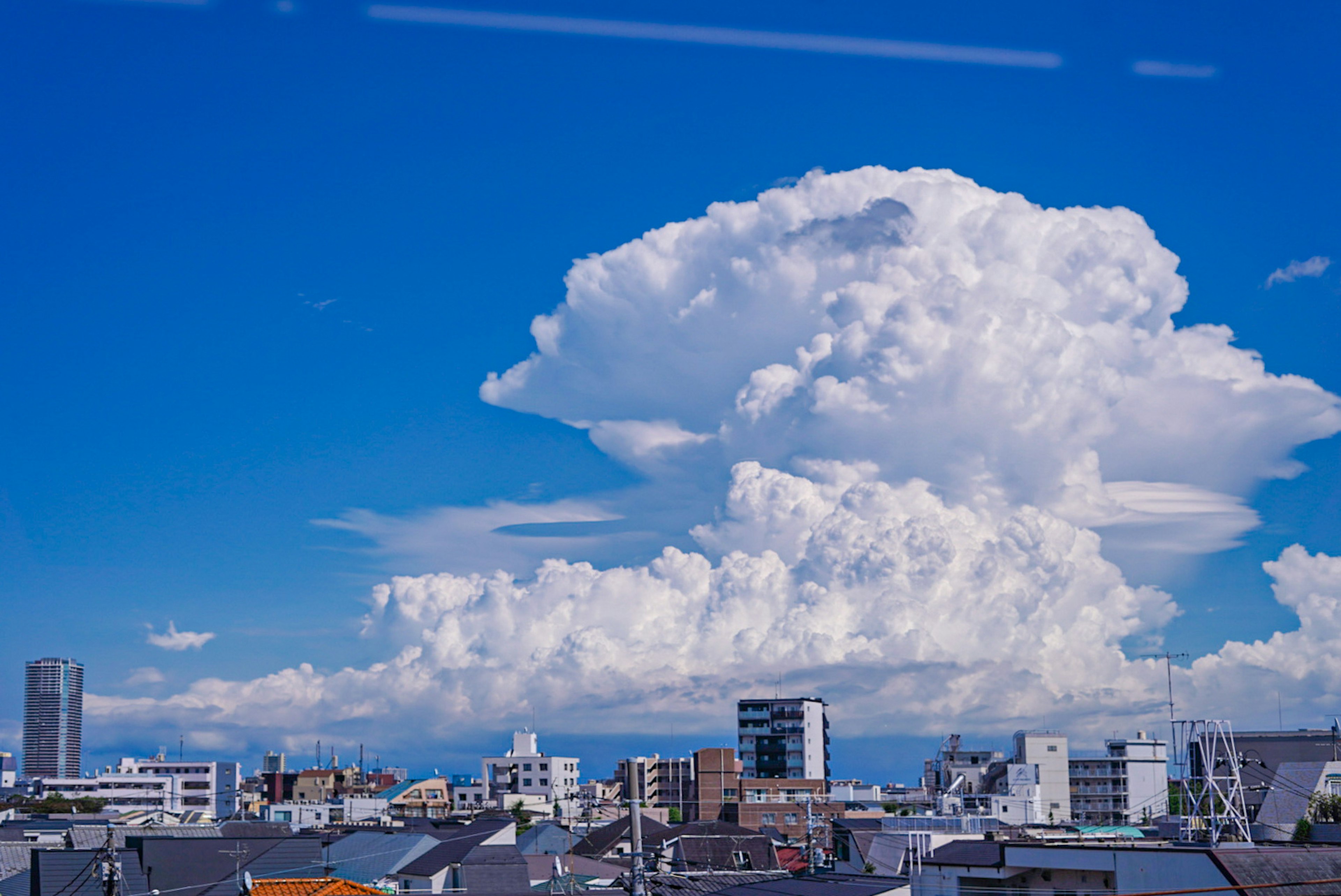 Gran nube flotando en un cielo azul sobre un paisaje urbano