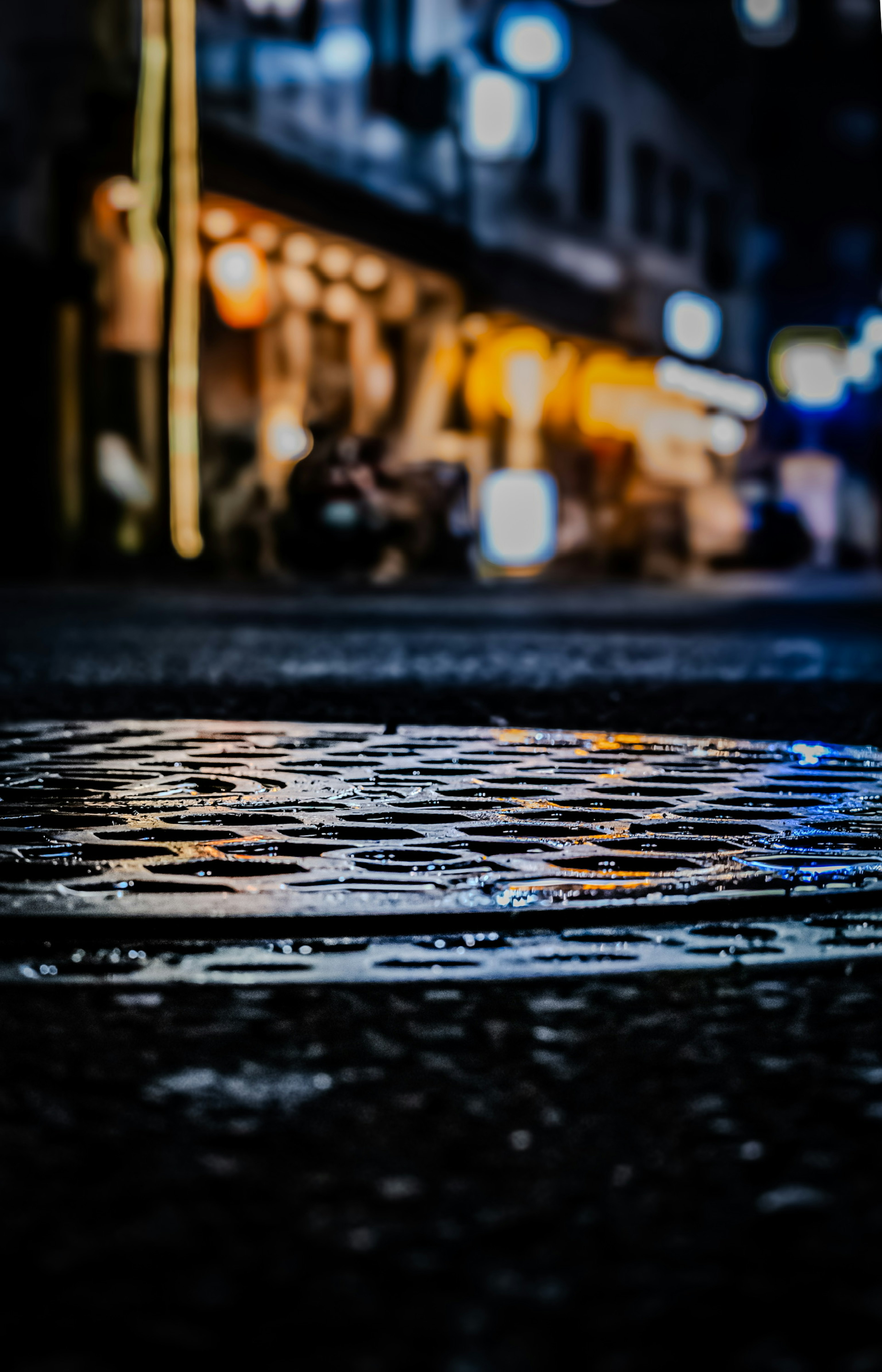 Tapa de alcantarilla reflejando las luces de la ciudad de noche