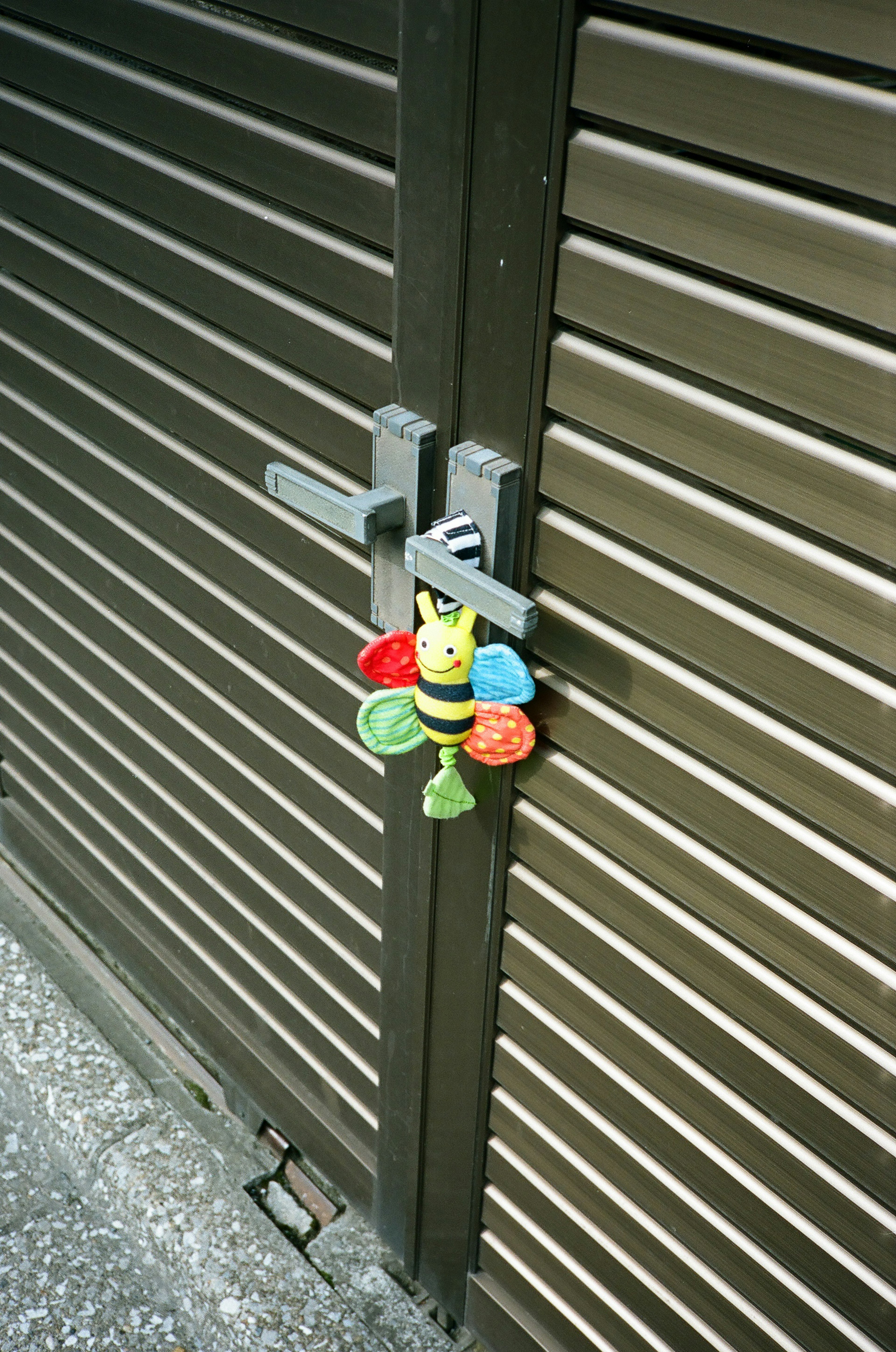 Candado colorido y juguete de abeja colgado en una puerta de metal