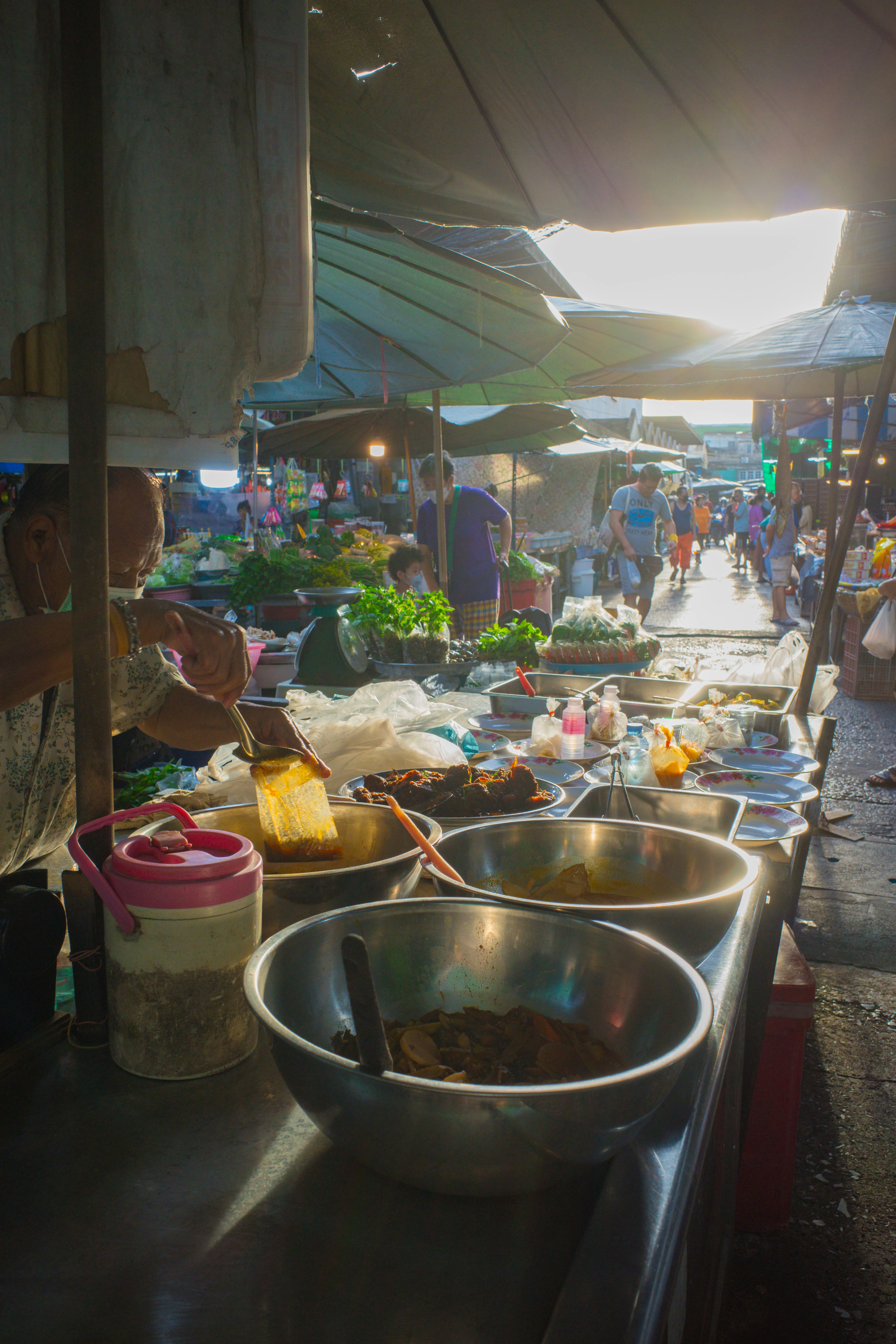 Puesto de mercado con cuencos e ingredientes frescos bajo sombrillas