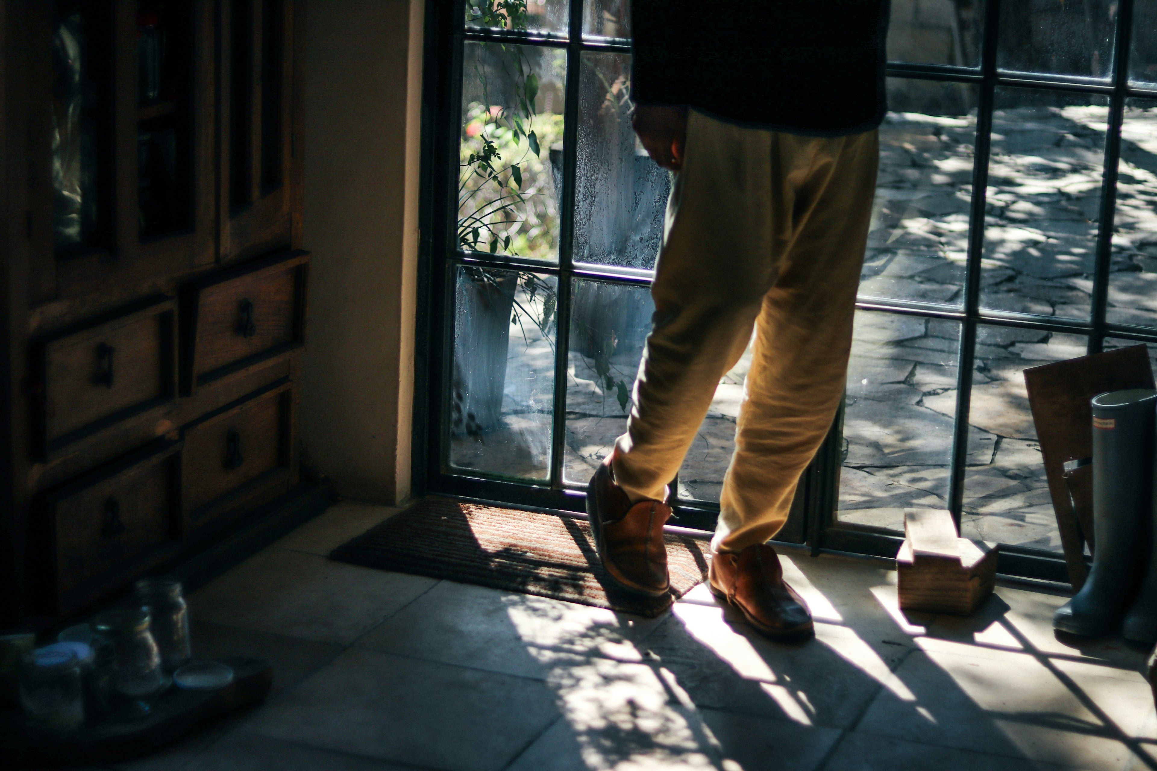 Foto von den Füßen und Schuhen eines Mannes neben einem Fenster