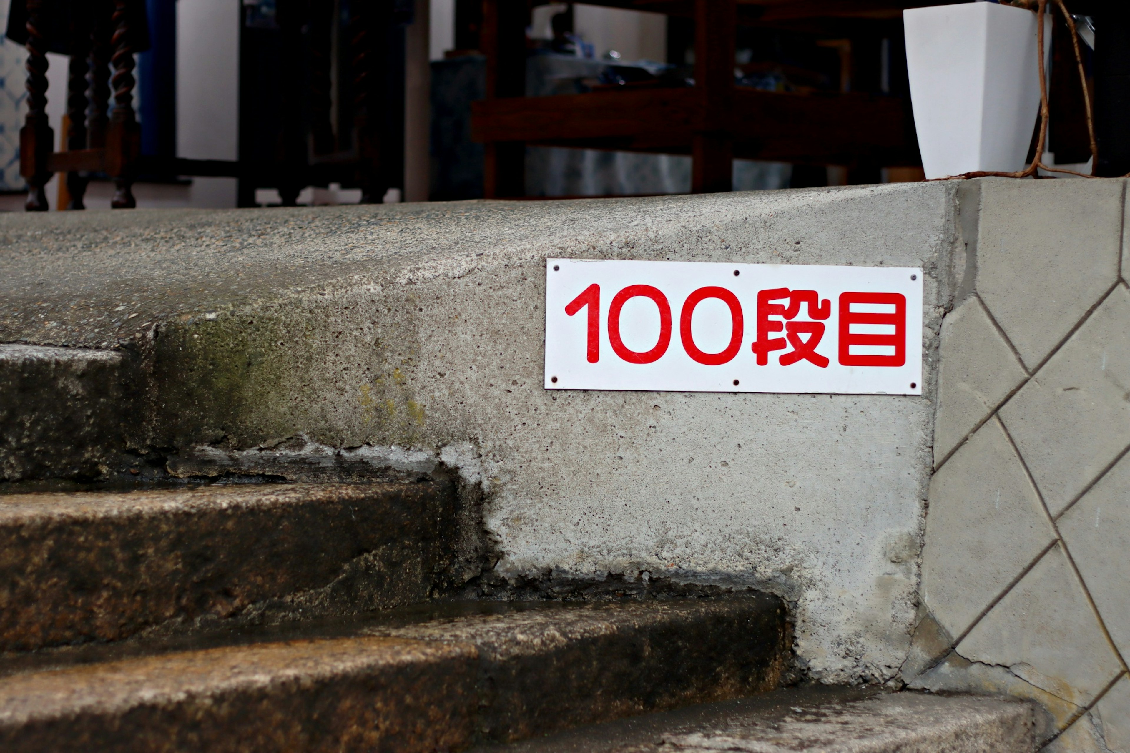 A white sign on the steps with red text reading 100段目