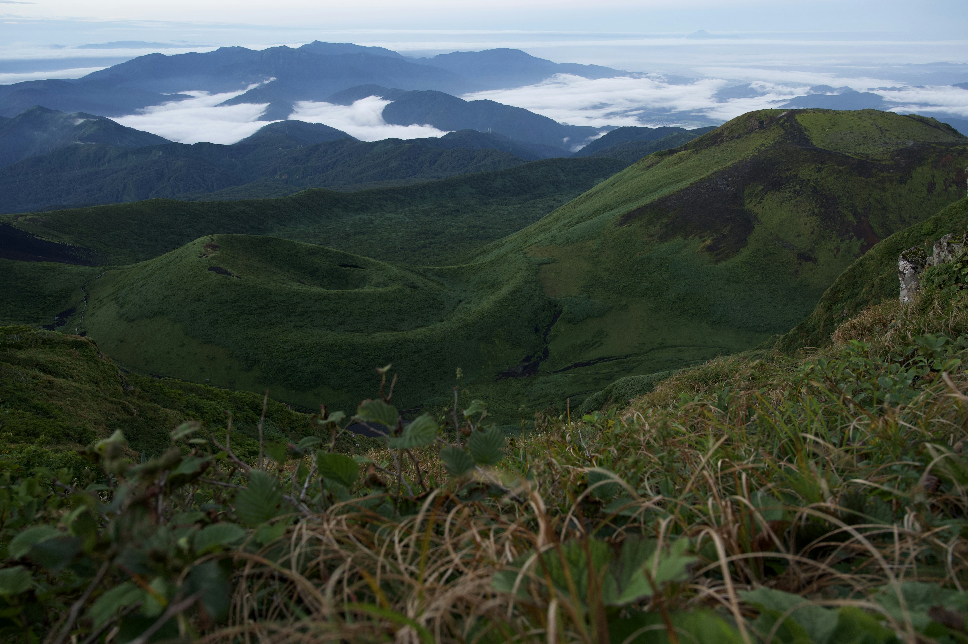 Scenic view of green mountains with a sea of clouds