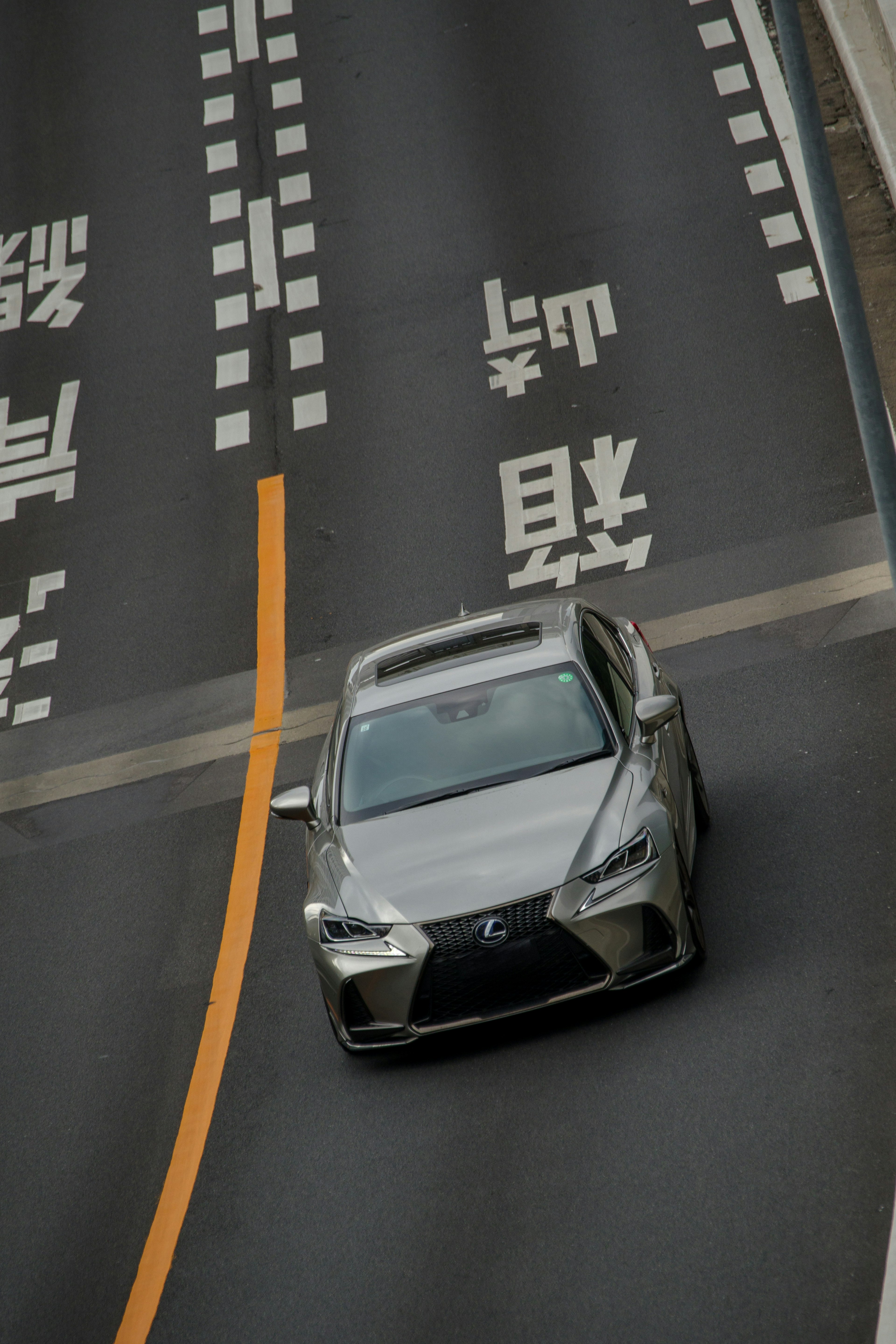 Silver Lexus turning on a road with painted markings