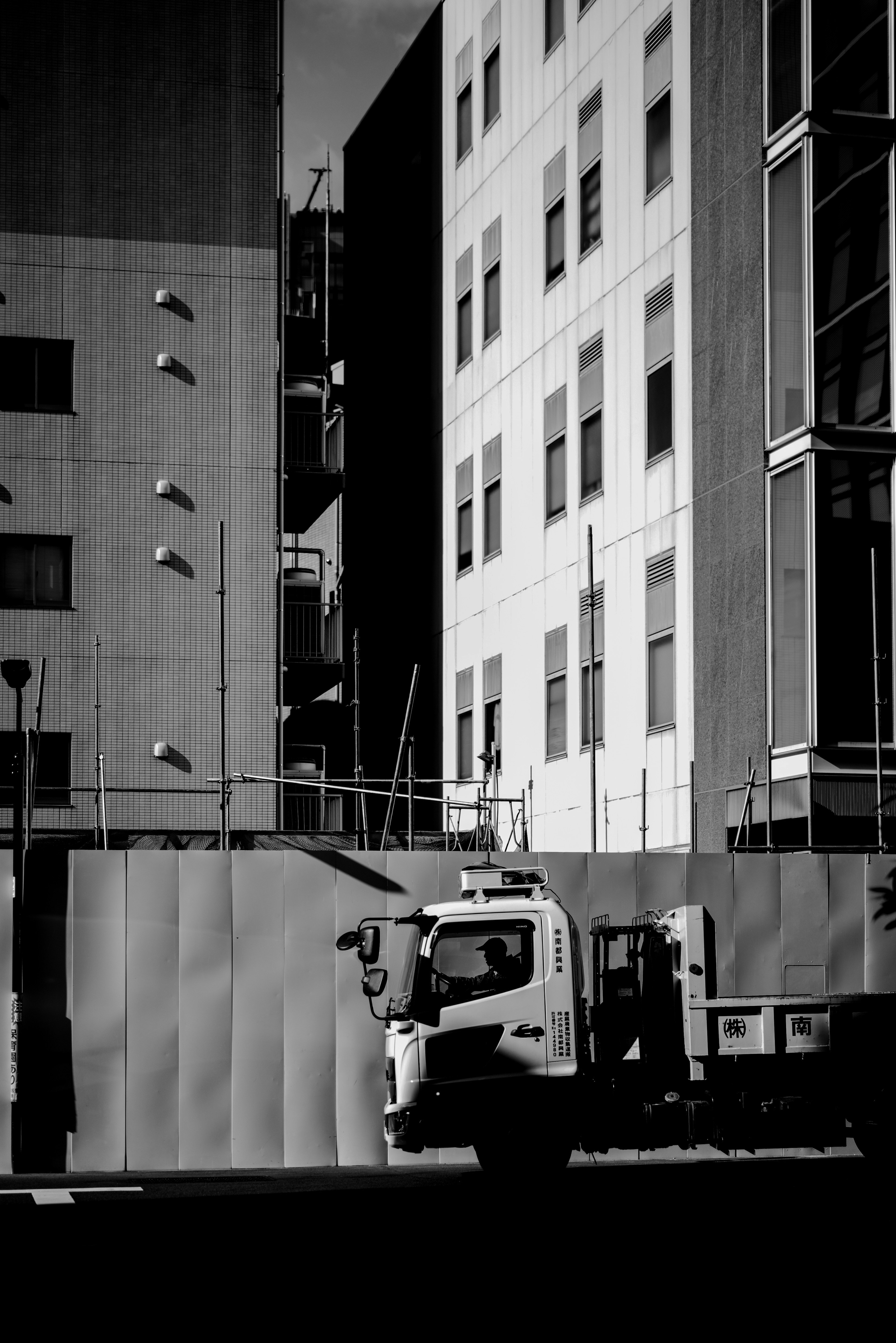 Scena urbana in bianco e nero con un camion in un cantiere