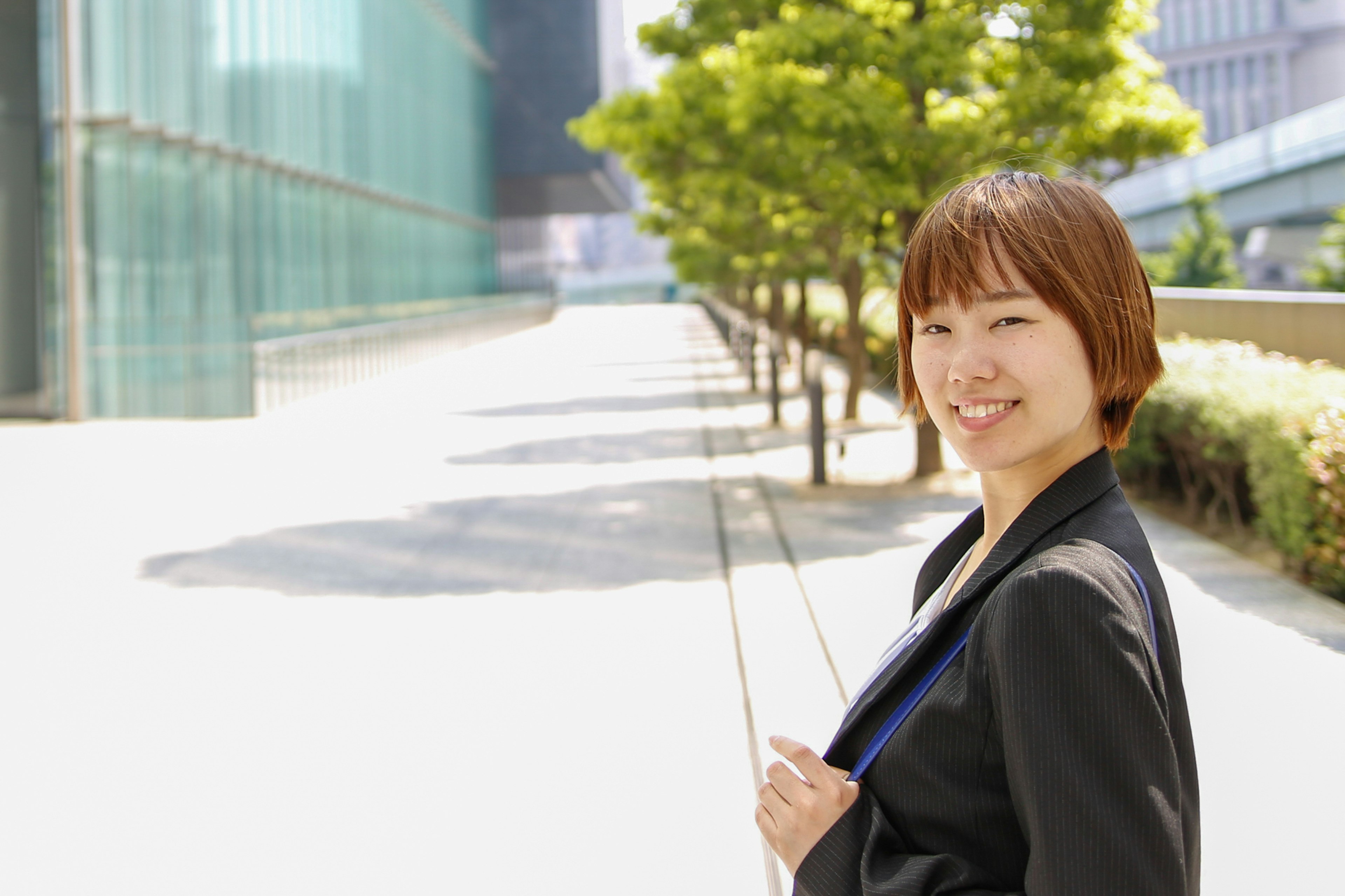 Smiling woman in business suit against urban backdrop with greenery