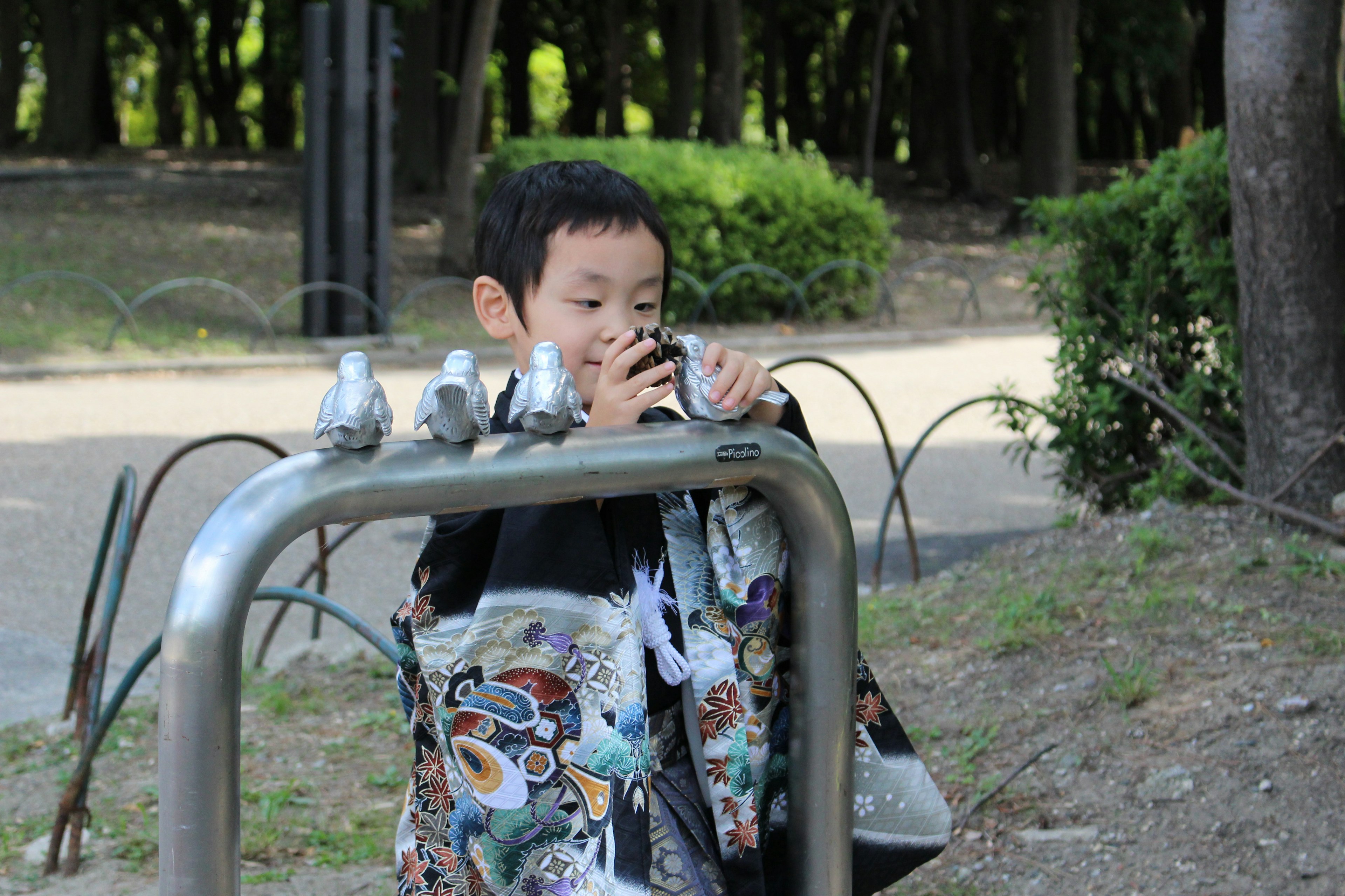 Un bambino che gioca in un parco appoggiato a una ringhiera metallica