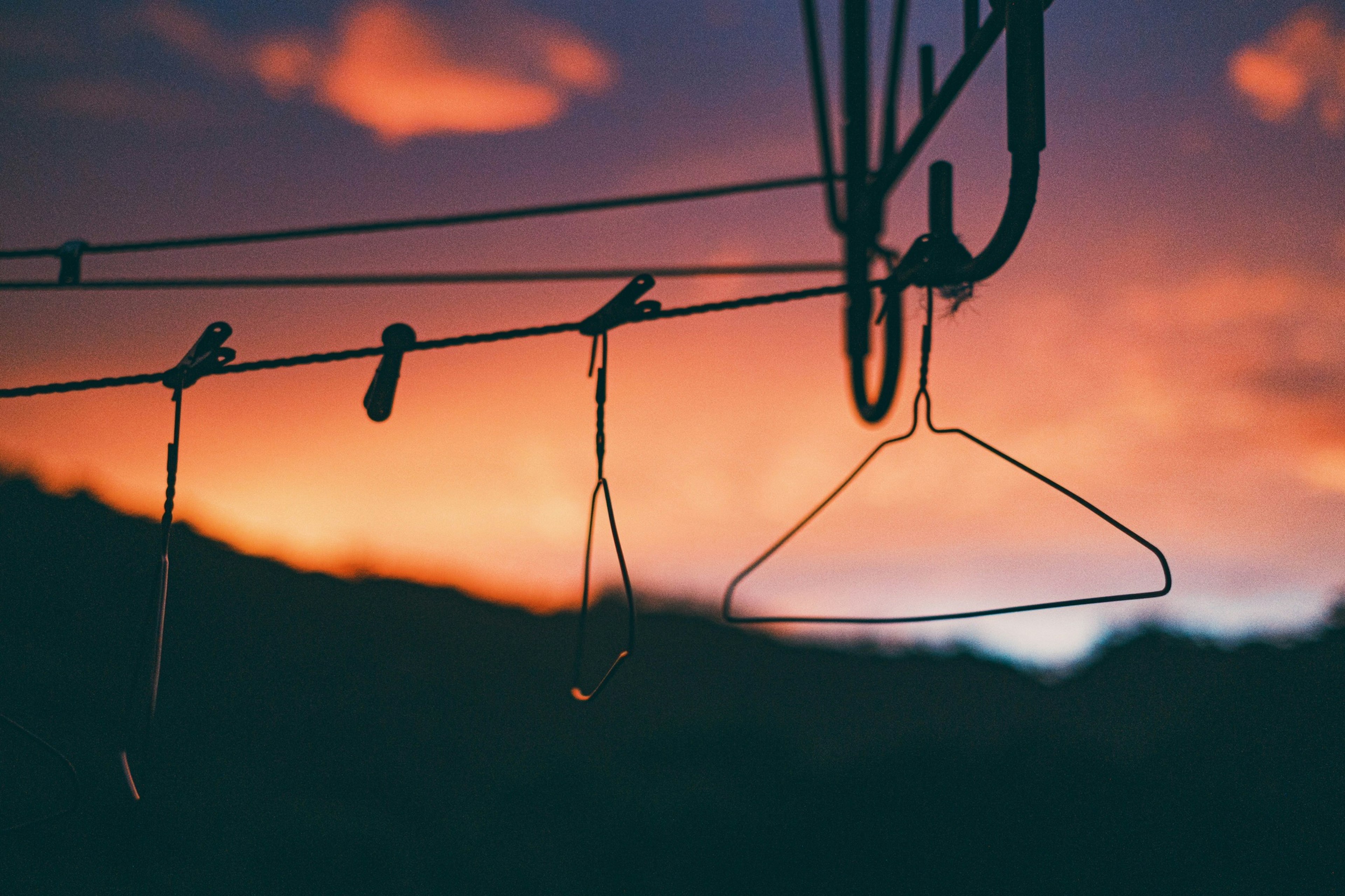 Image of hangers and clothespins against a sunset sky