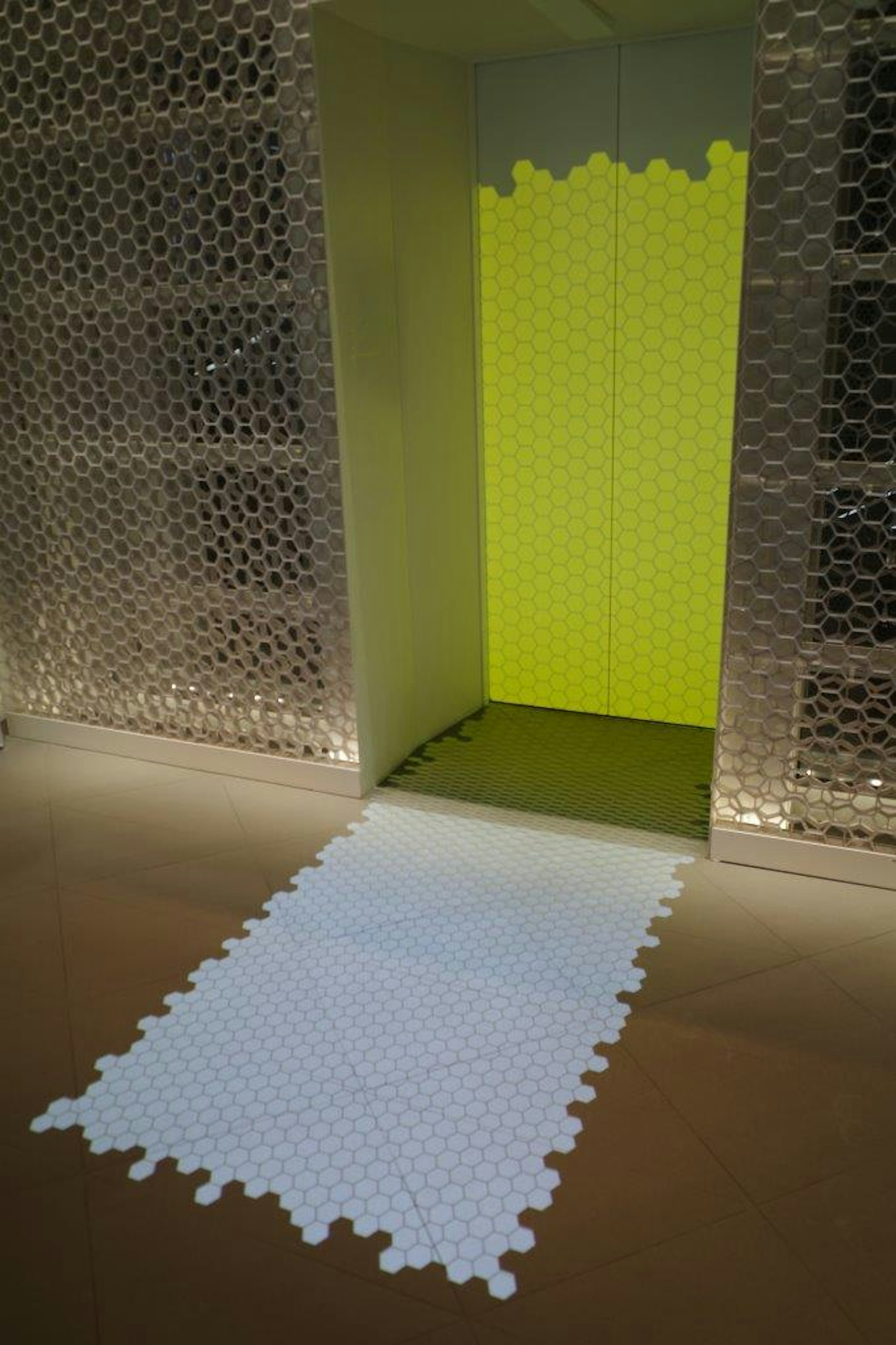 Un tapis en forme de puzzle blanc mène à un mur jaune vif à l'entrée