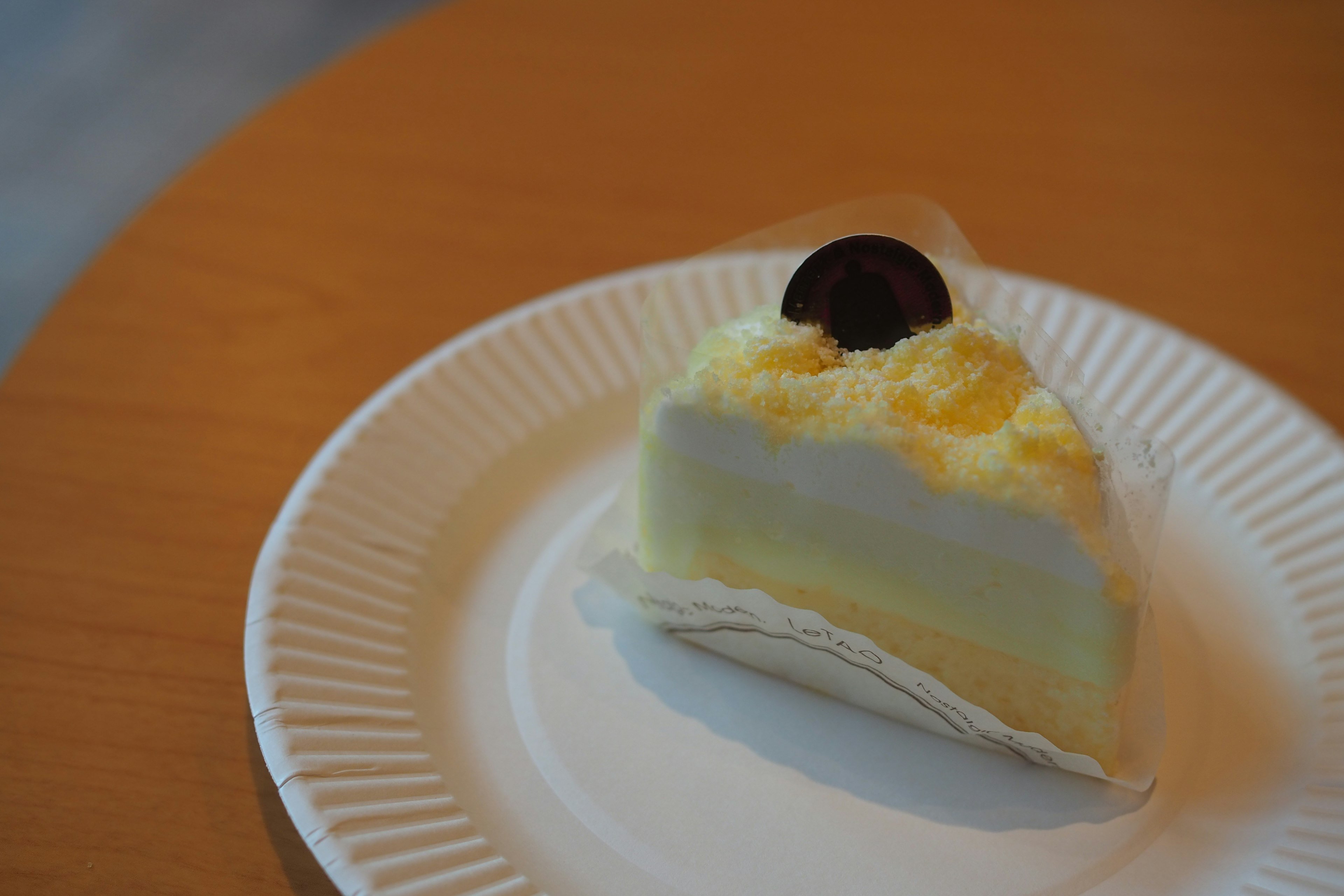 A slice of cake topped with cream and a chocolate disc