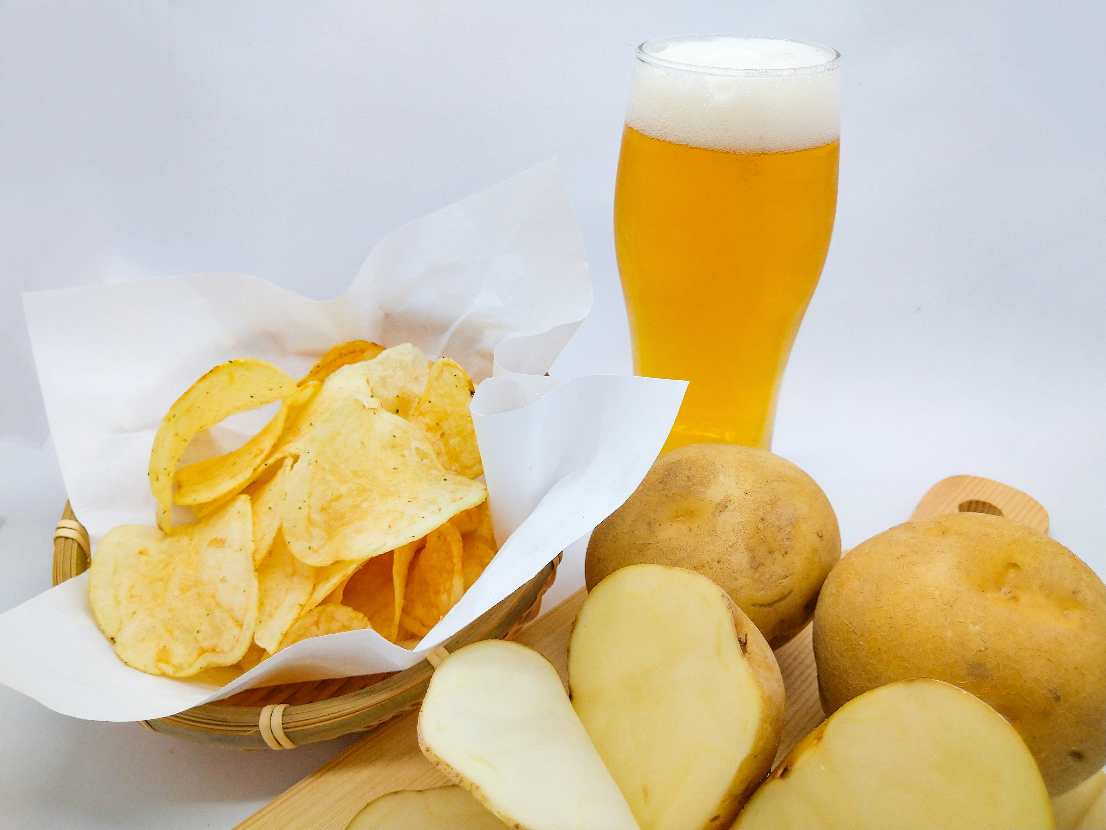 A basket of potato chips with a glass of beer and fresh pears