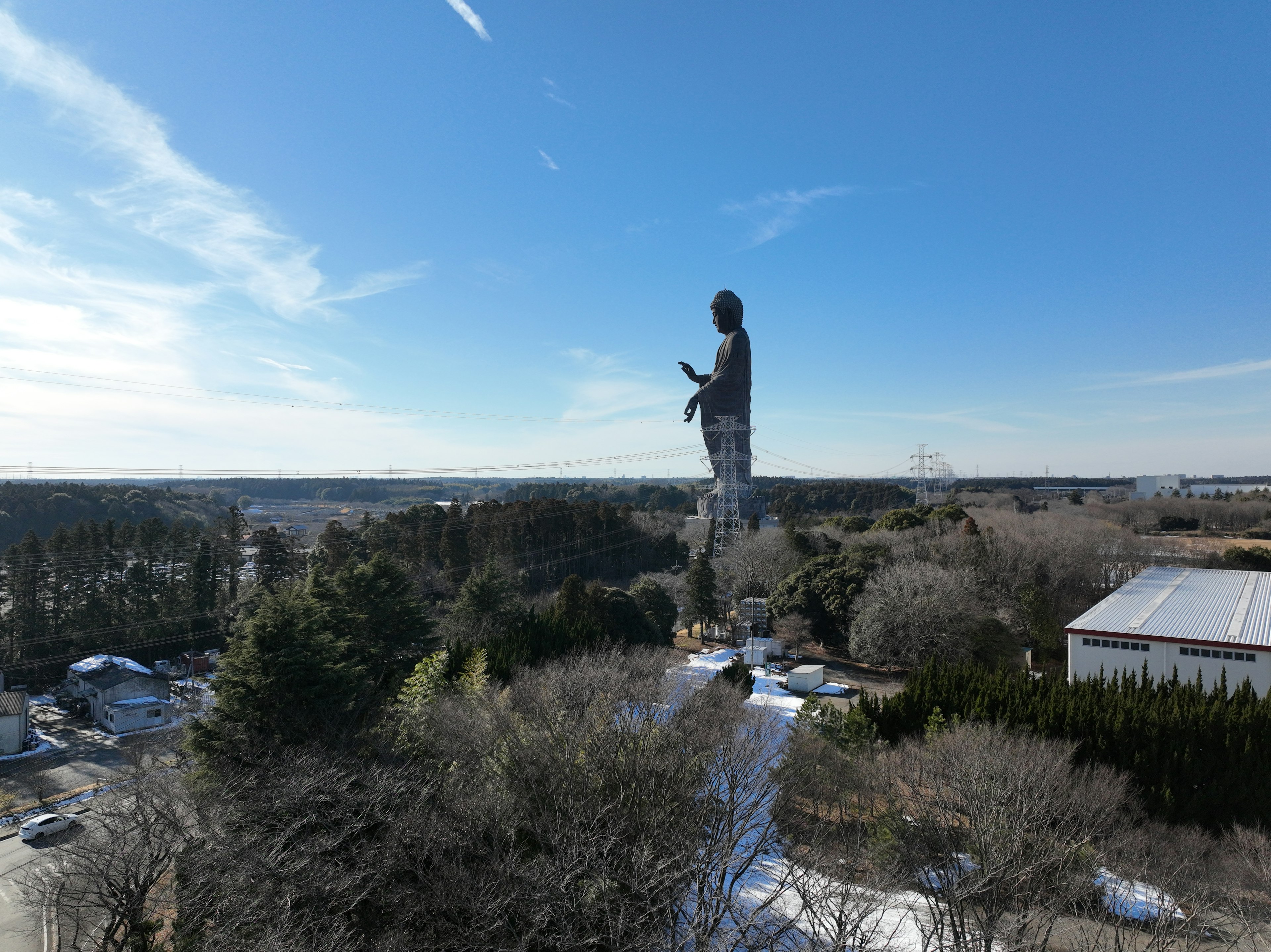 A large statue stands overlooking a landscape with blue sky and clouds