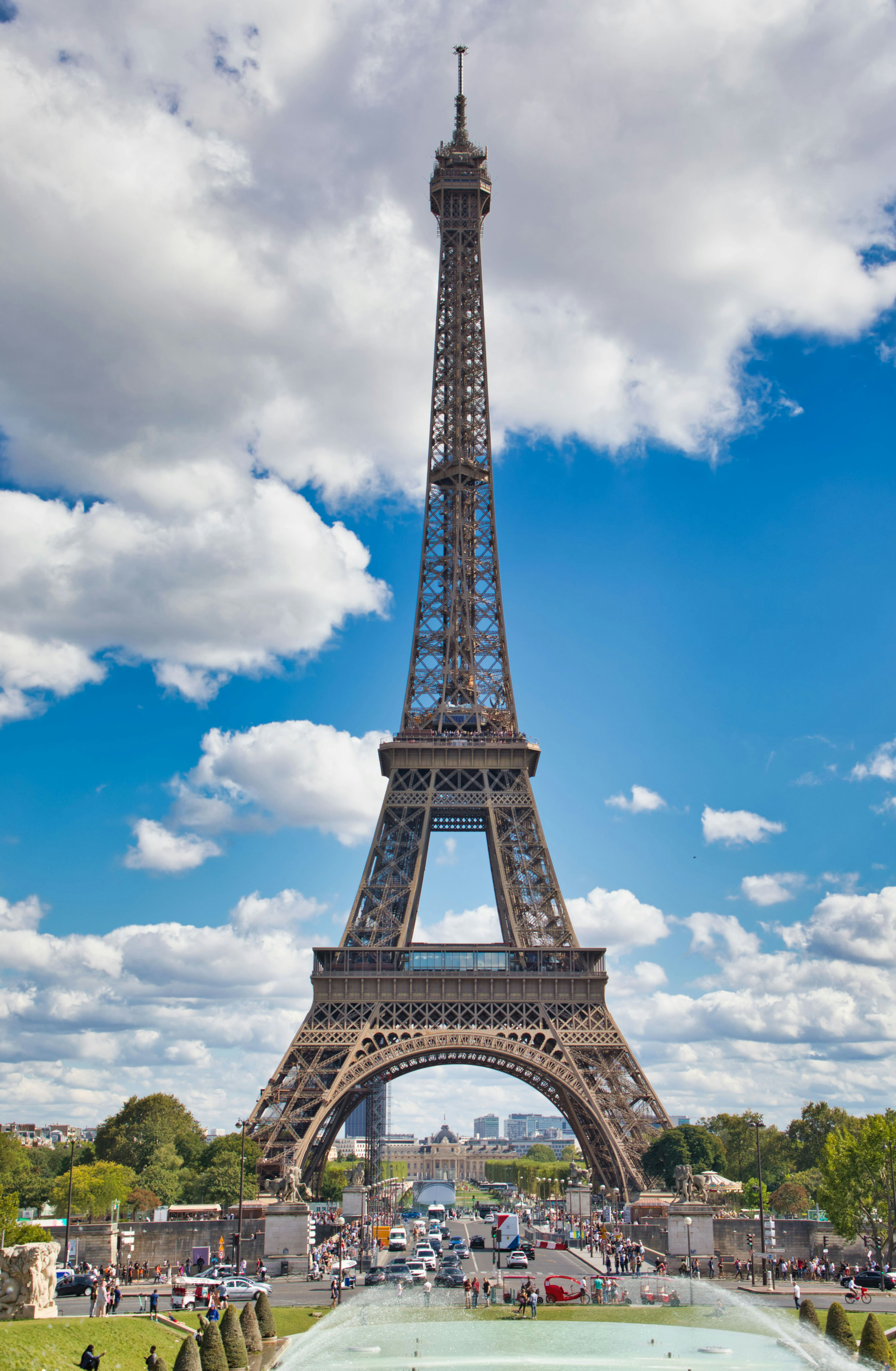 Menara Eiffel di bawah langit biru cerah dan awan putih