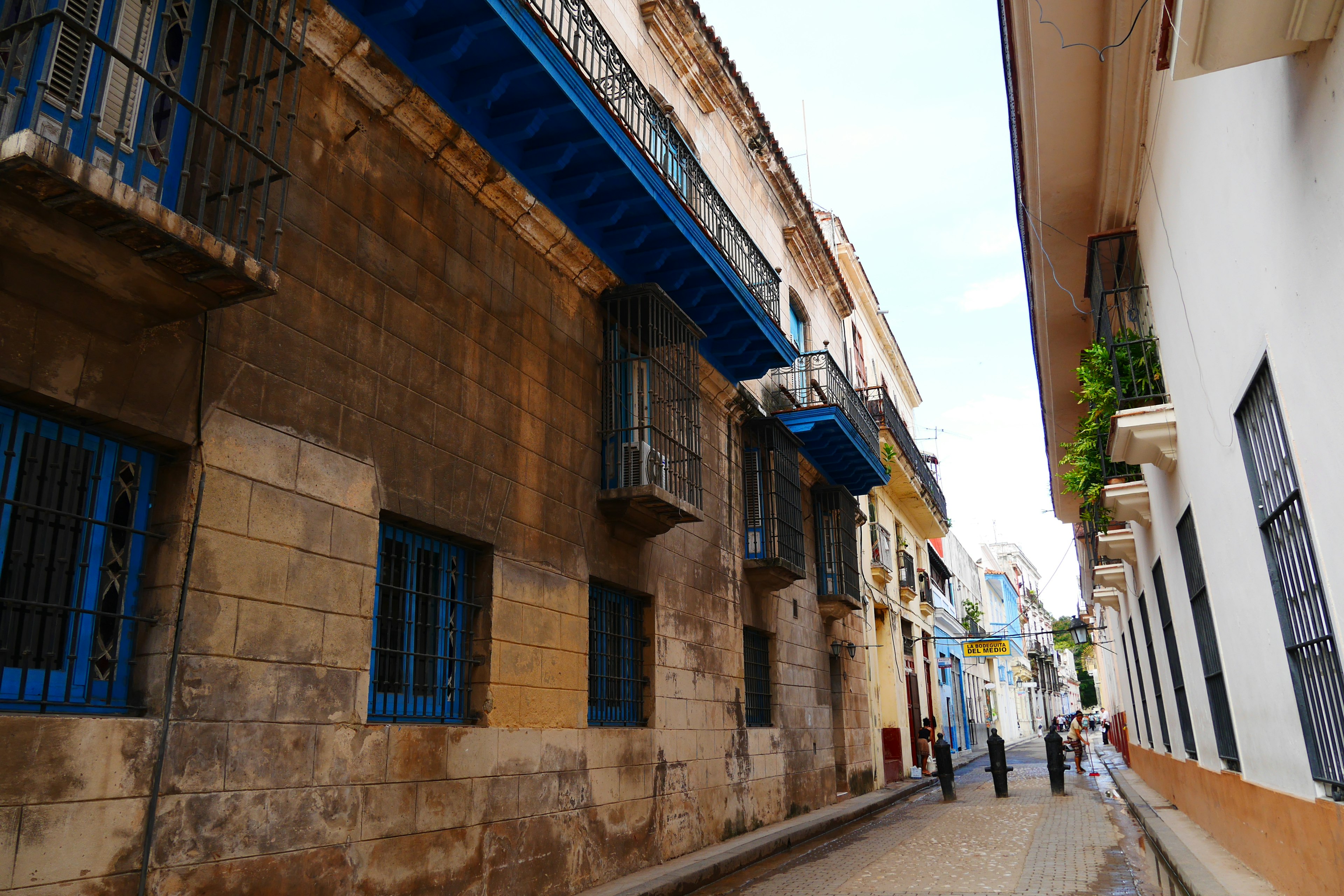 Narrow street featuring old stone buildings with blue balconies