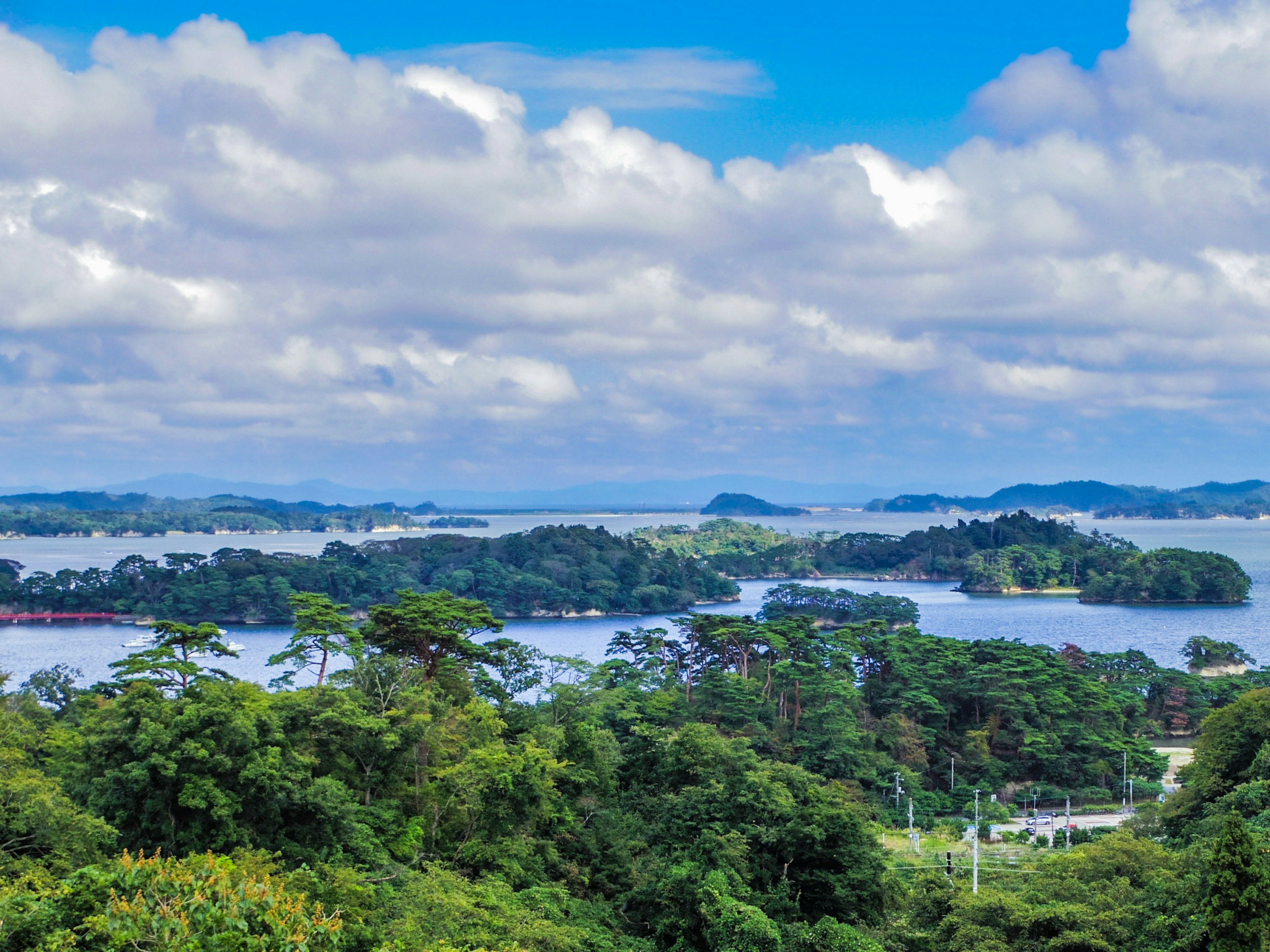 藍天和雲朵下，點綴著茂盛綠樹的島嶼風景