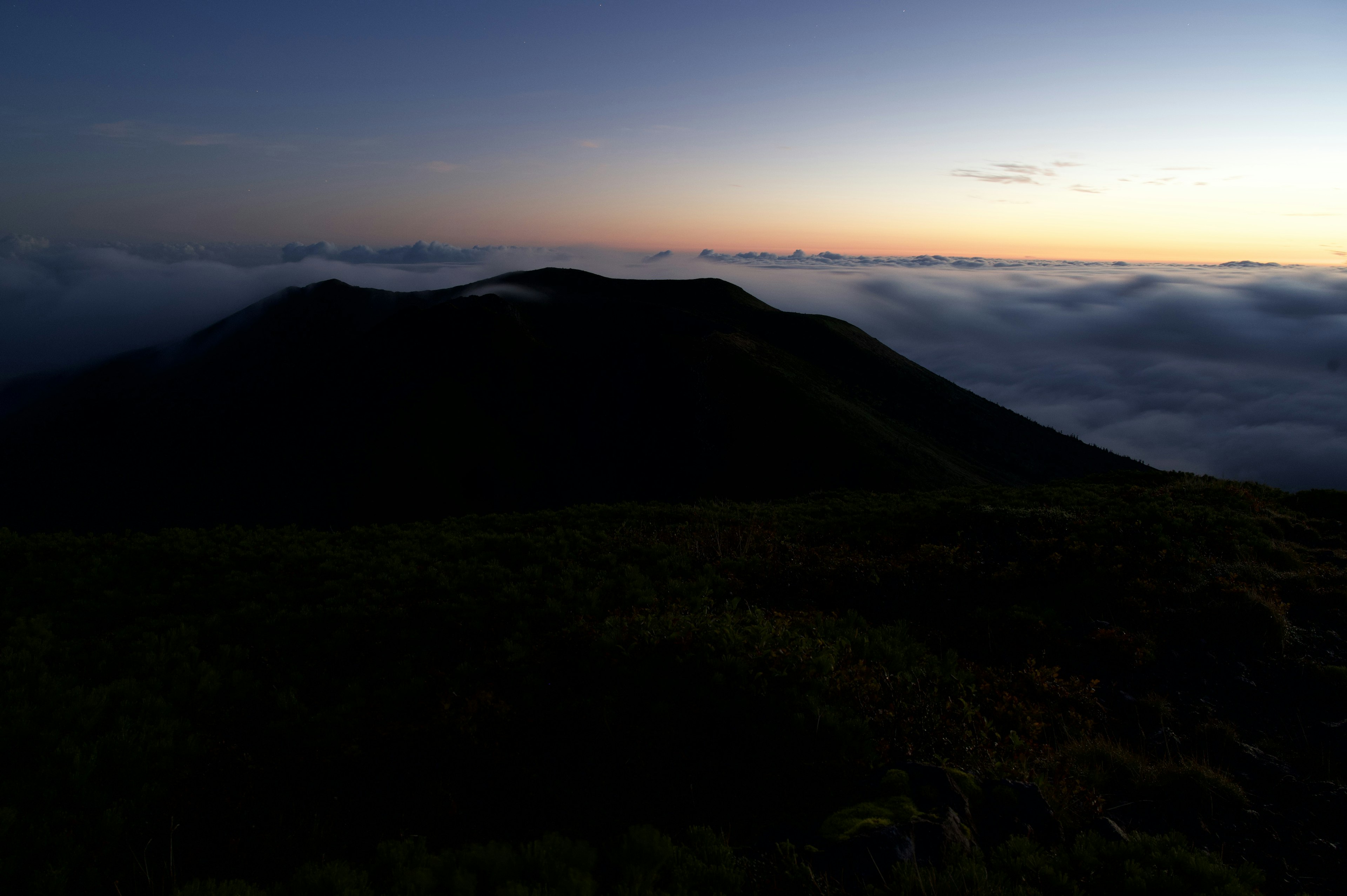 山のシルエットと雲海が広がる夕暮れの風景