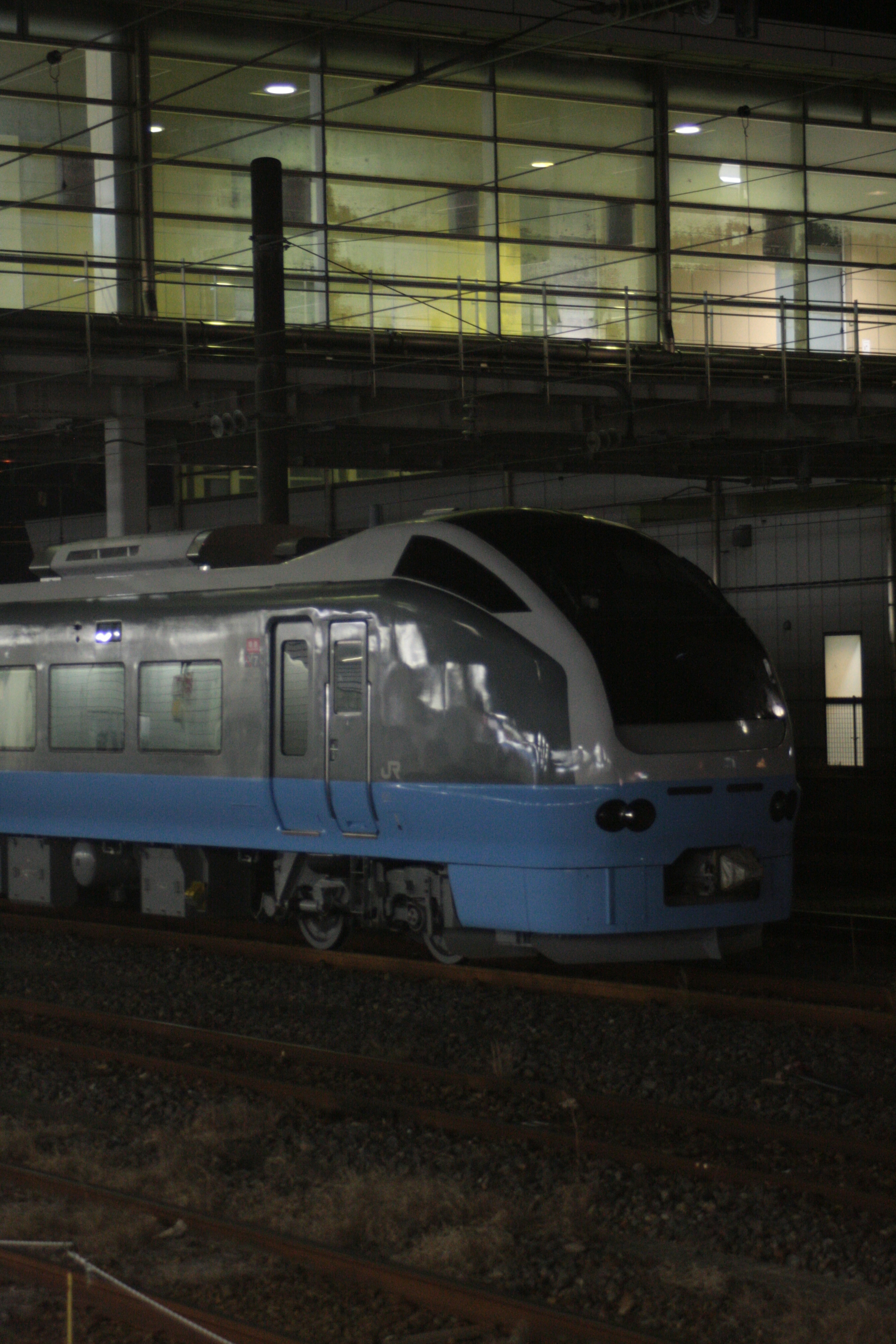 Blue train parked at a station platform in a nighttime setting