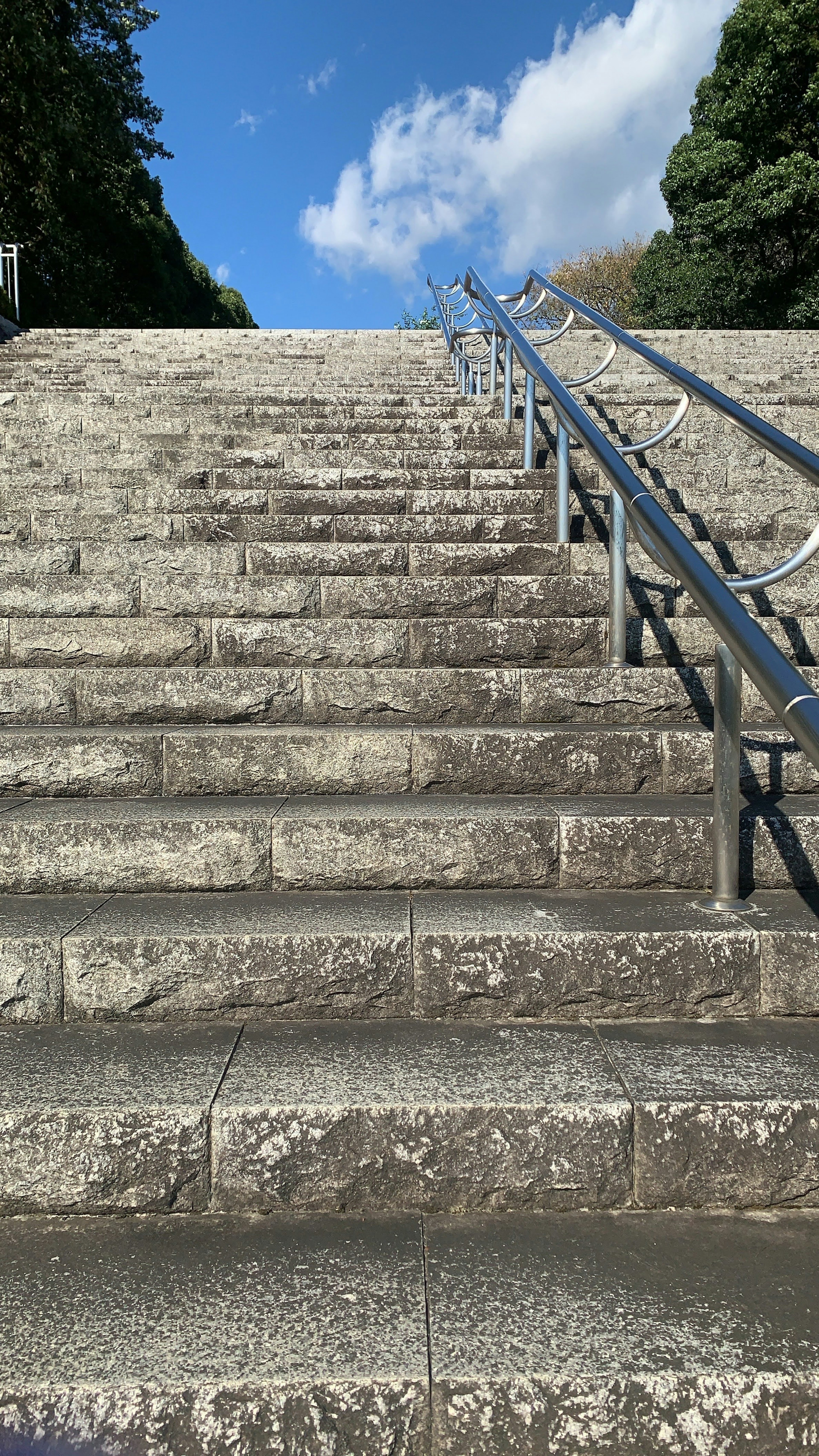 View of stone steps leading upwards under a blue sky with white clouds