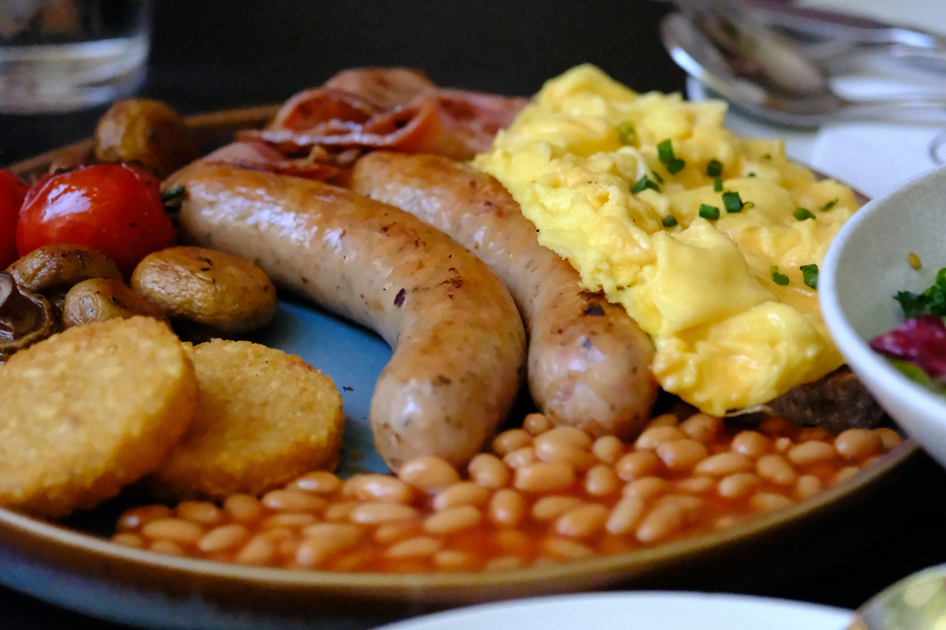 Ein Frühstücksteller mit Würstchen, Rührei, Bohnen, Hash Browns und Tomaten