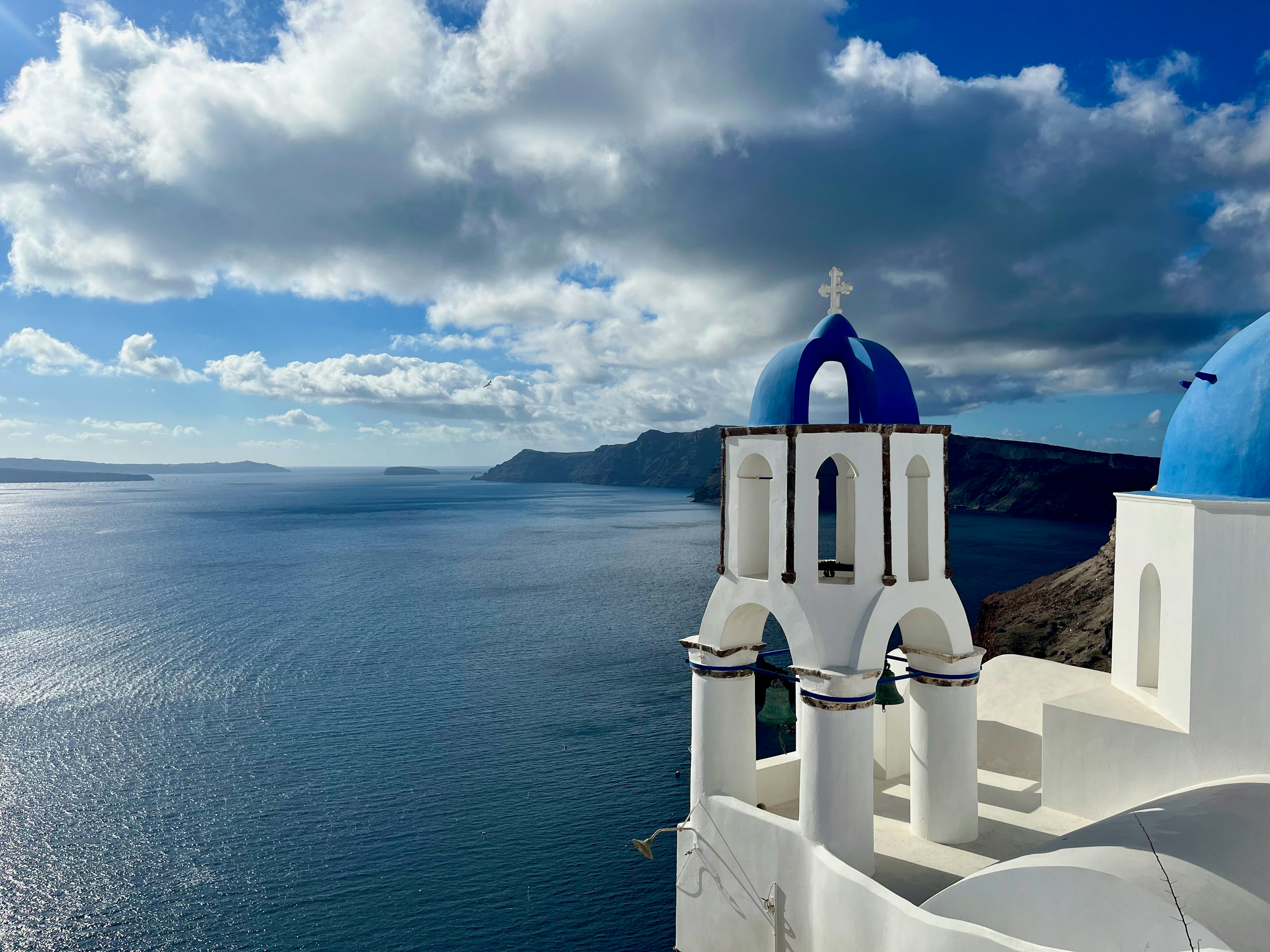 Gereja dengan kubah biru menghadap ke laut dan awan