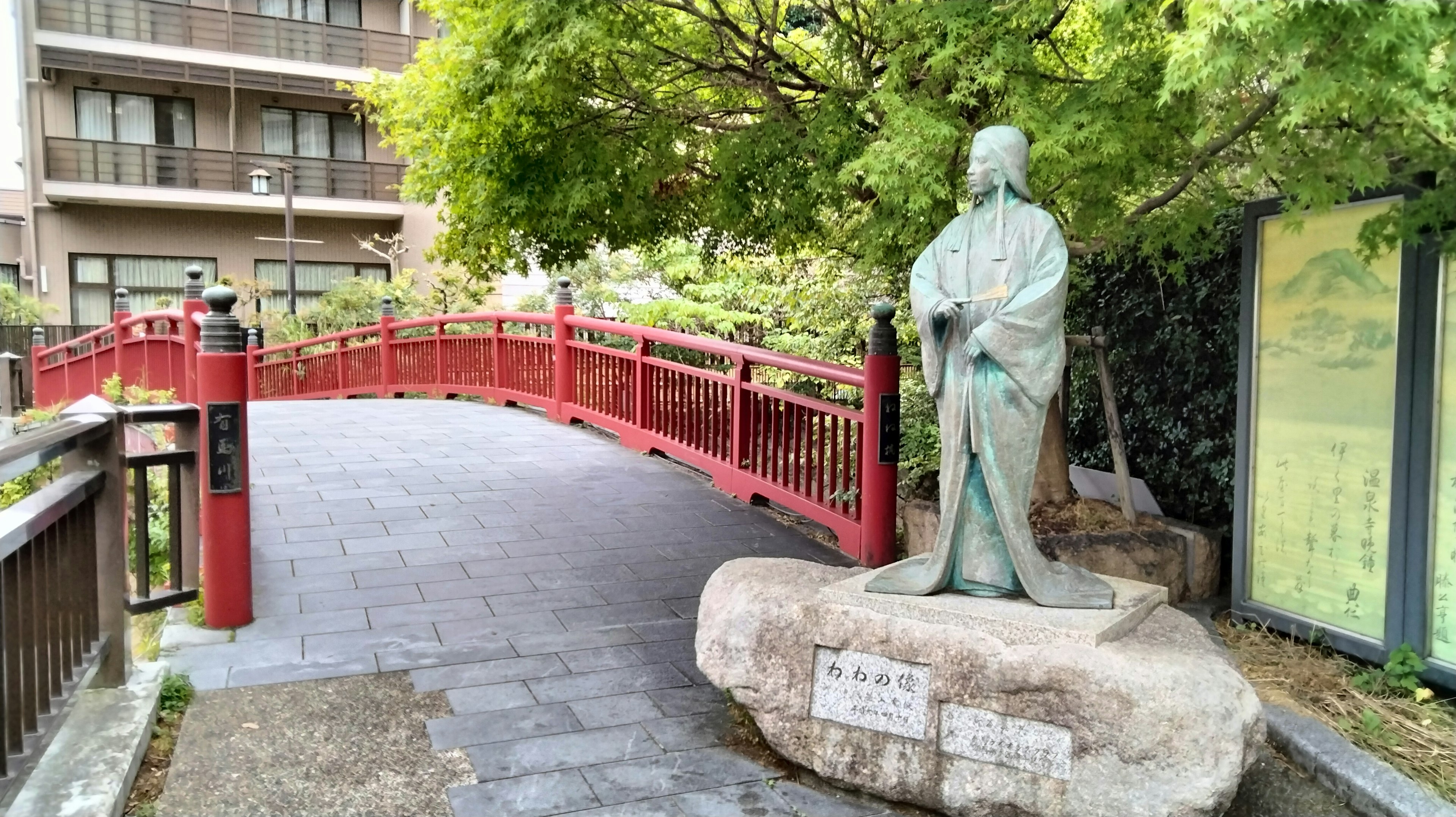 Parkansicht mit einer roten Brücke und einer Statue