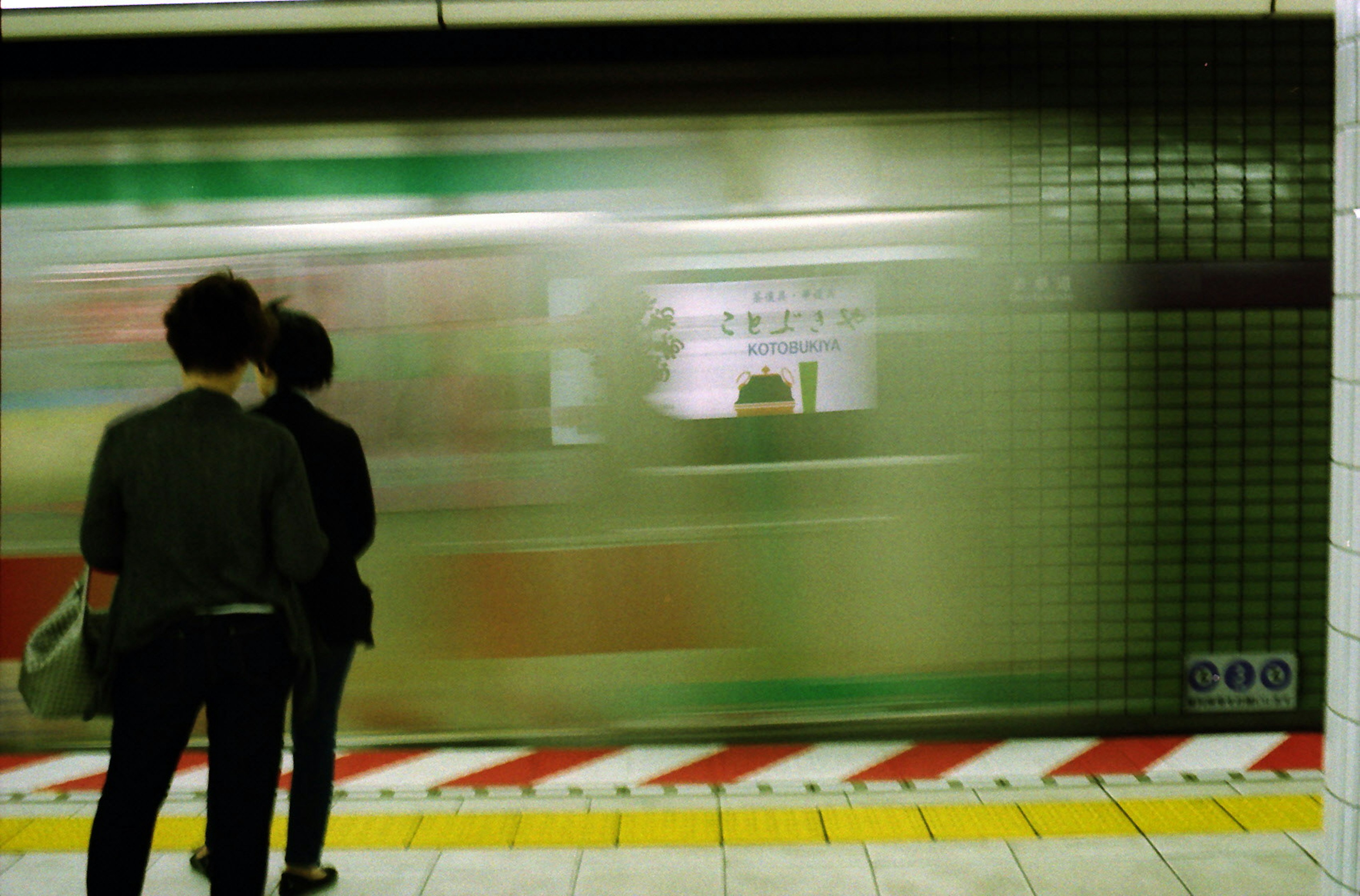 Silhouettes de deux personnes attendant sur un quai de métro avec un train passant