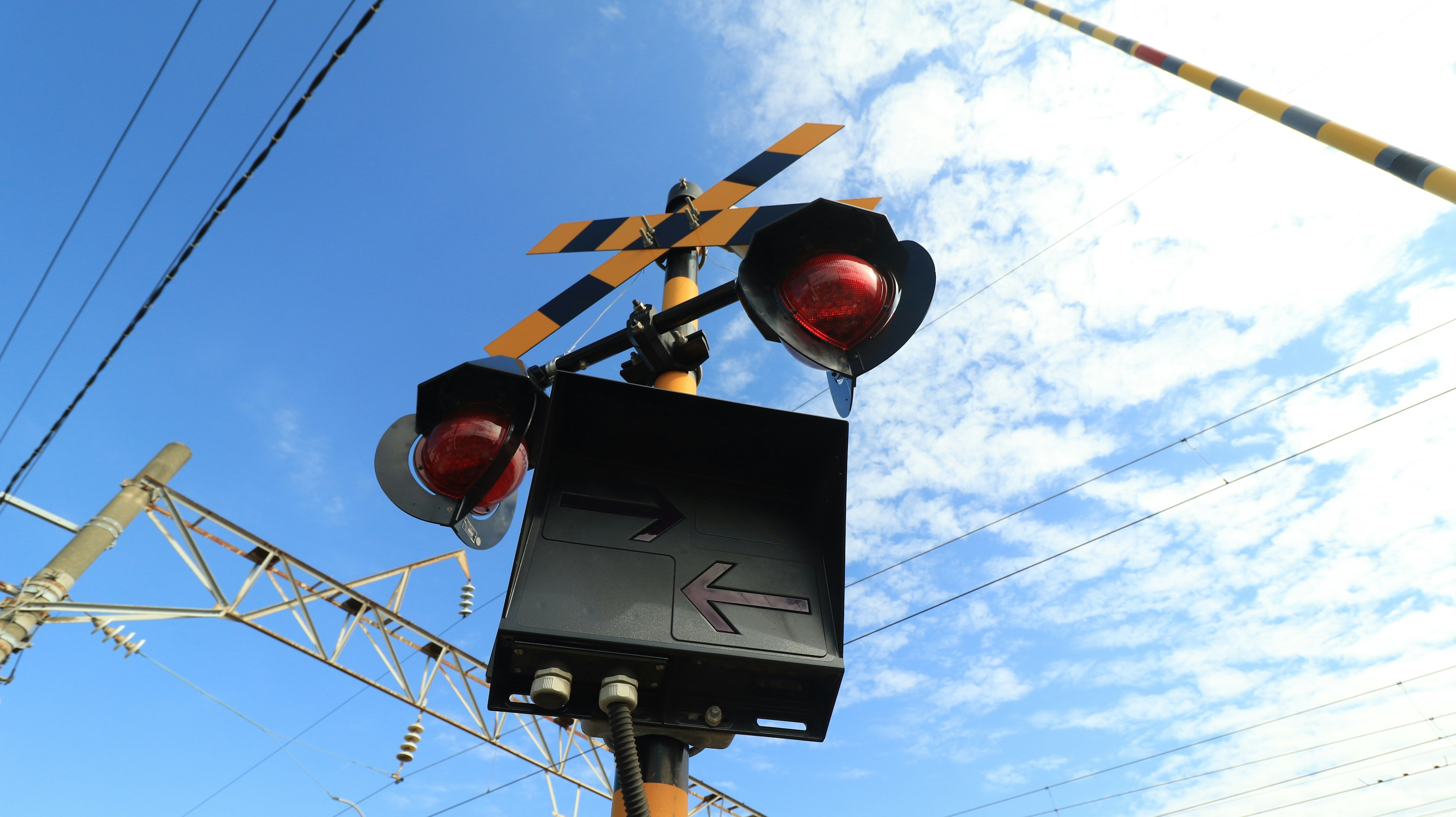 Railroad signal with red warning lights against a blue sky