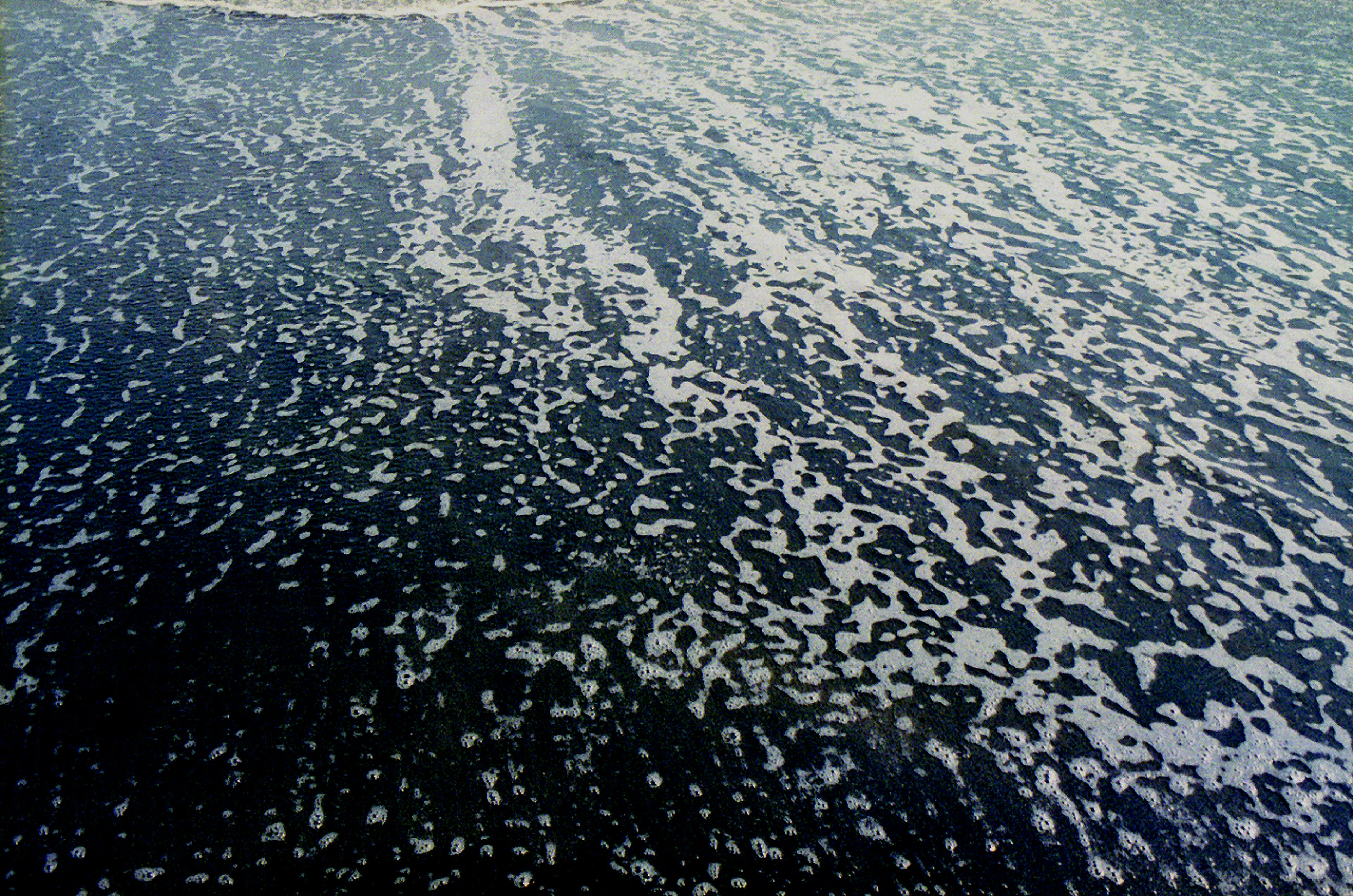 Superficie de agua azul mostrando espuma y patrones de olas