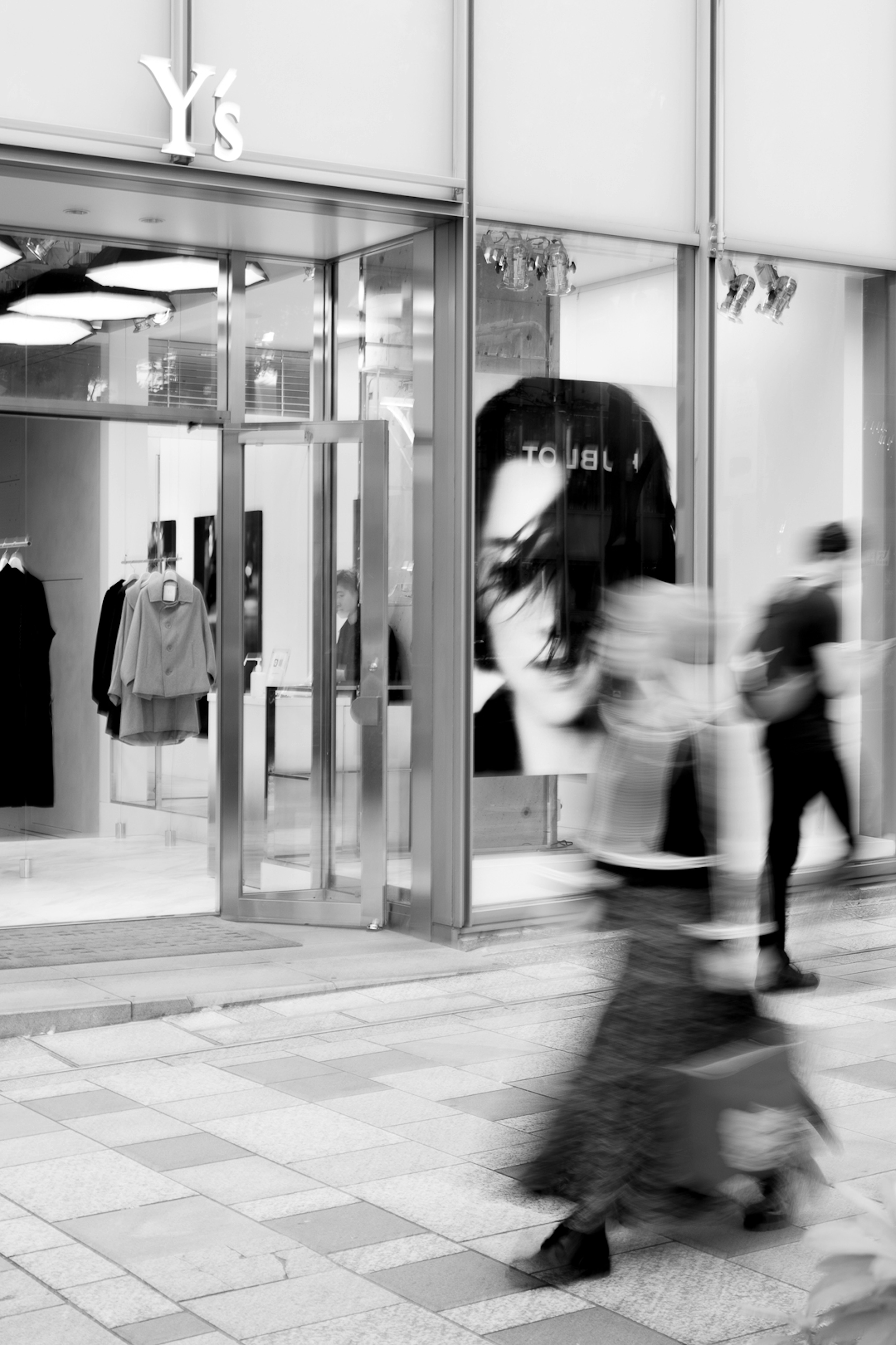 Black and white image of people walking past Ys store