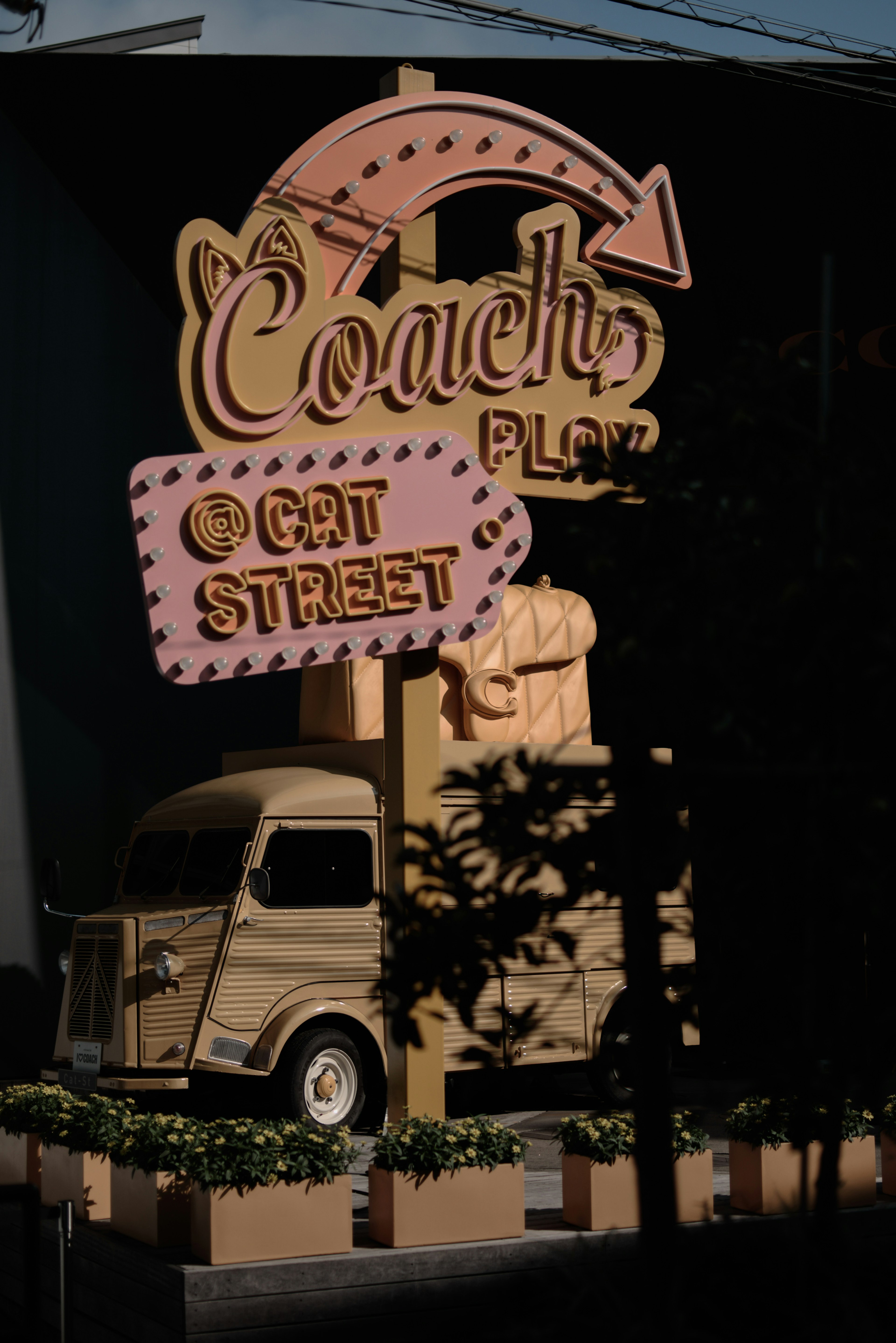 Schild für Coach Plaza mit einem kleinen Lastwagen auf der Cat Street