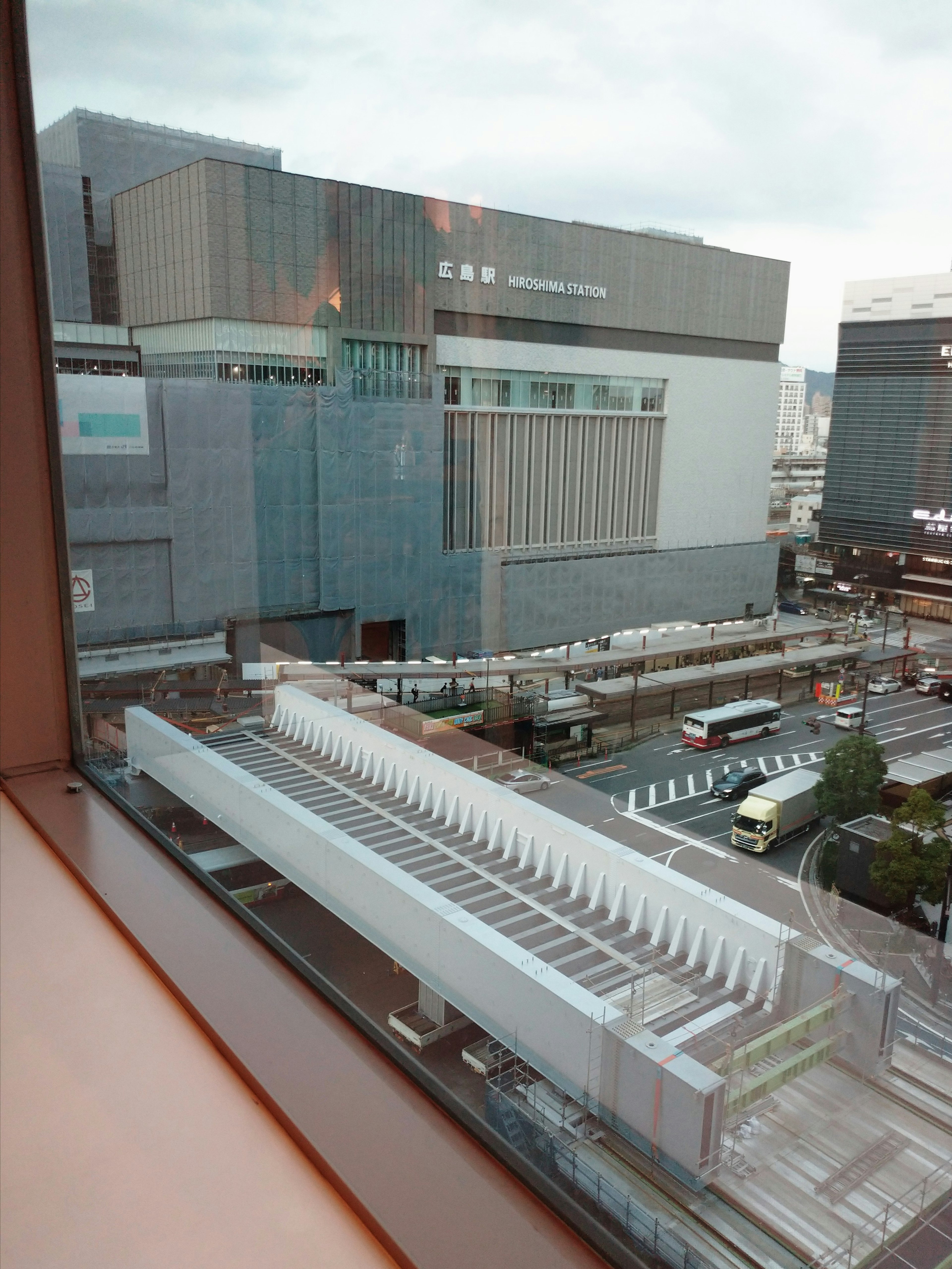 Urban landscape featuring modern buildings and a train station view under a cloudy sky