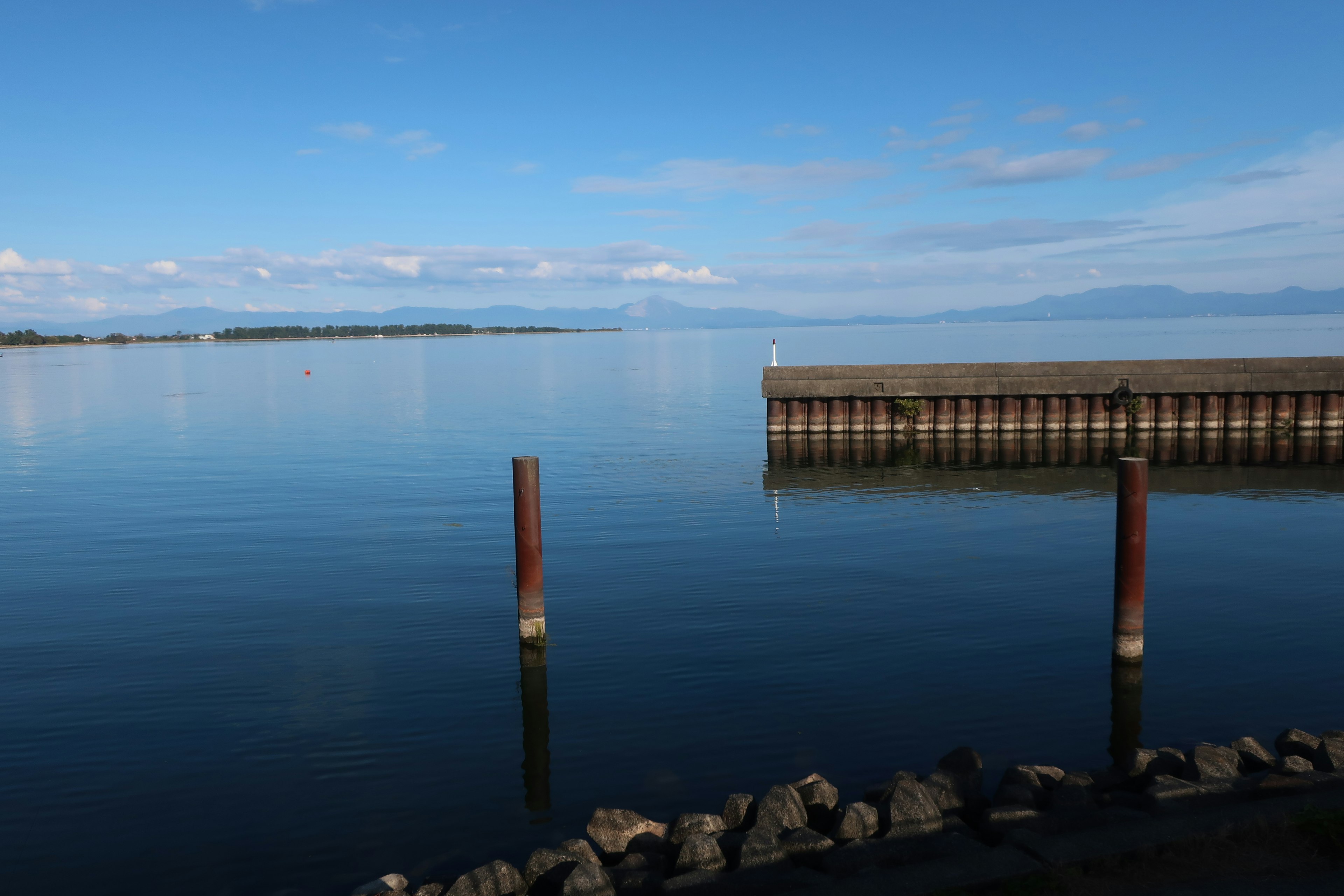 Eine ruhige Uferansicht mit klarem blauen Himmel und ruhigem Wasser