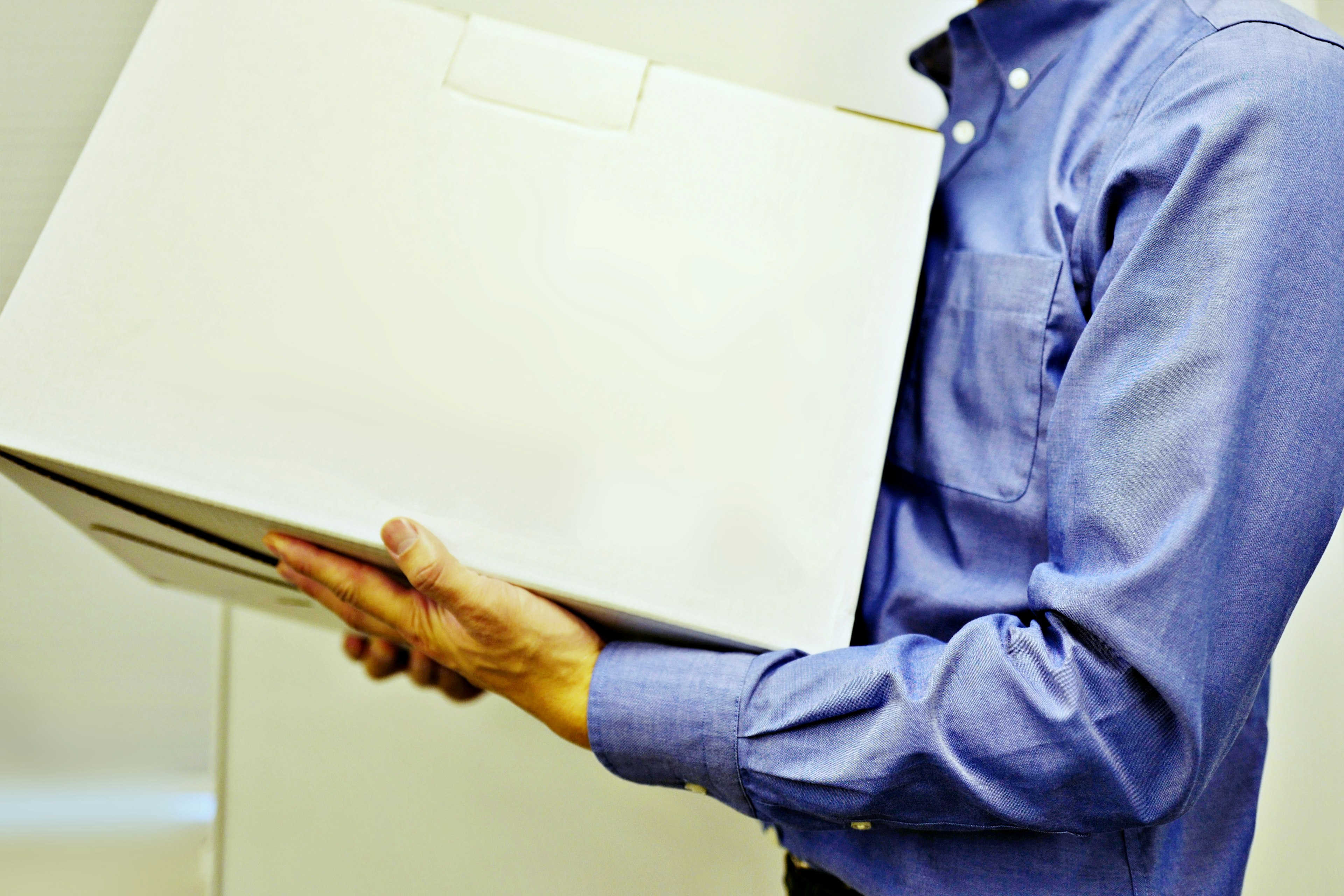 Man in blue shirt holding a white box