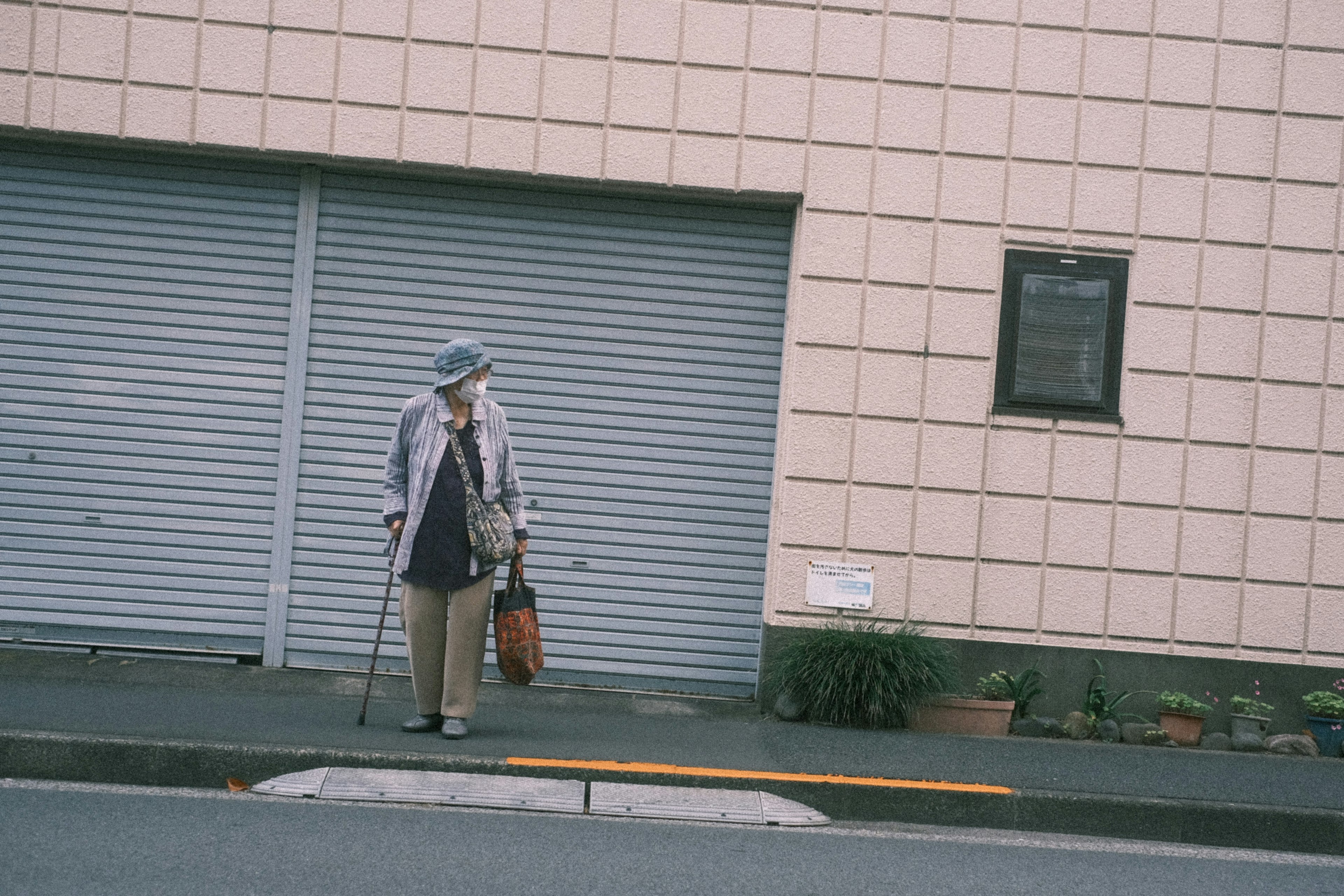 Femme âgée portant un chapeau violet clair se tenant devant un mur