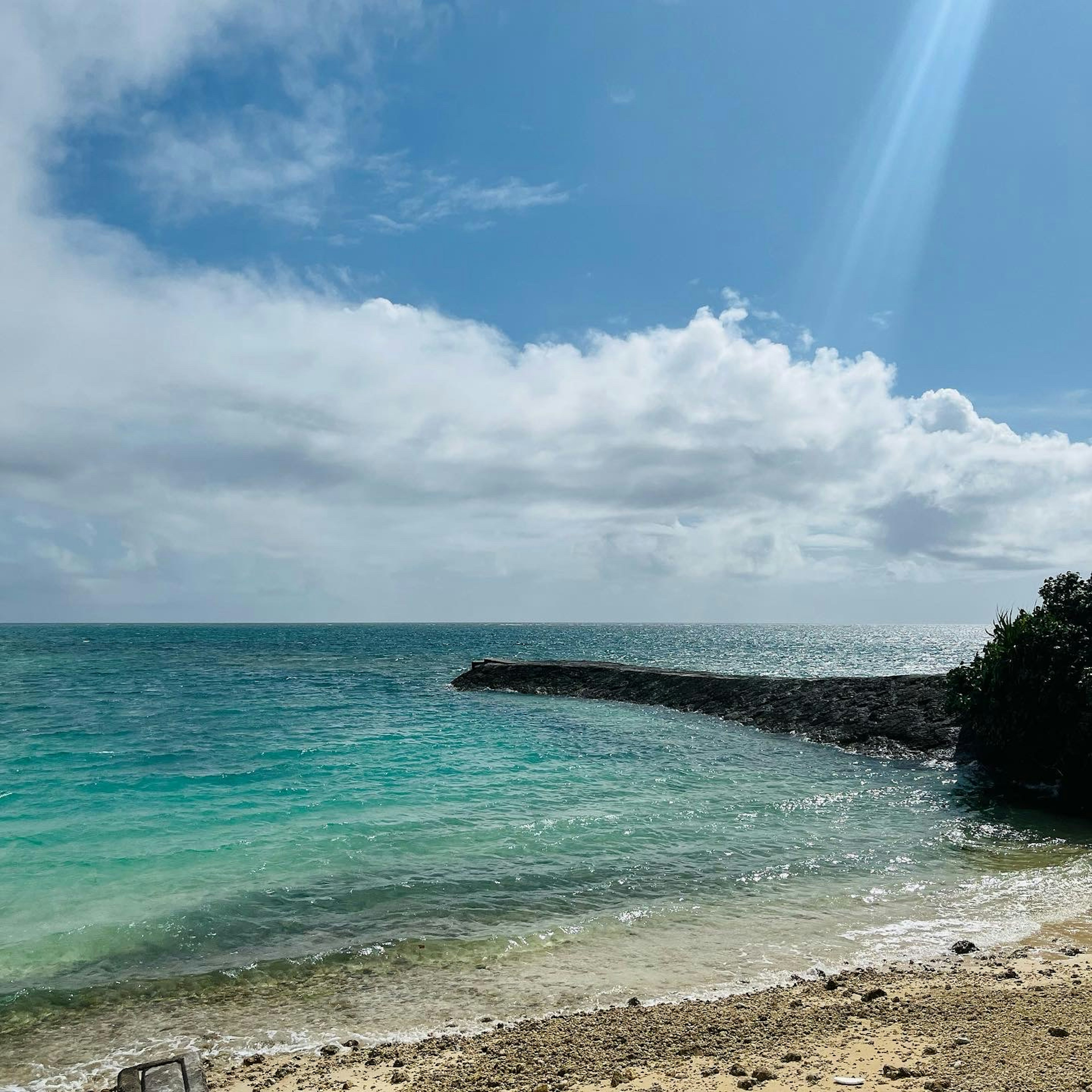 Vue pittoresque d'une plage avec de l'eau turquoise et un ciel nuageux